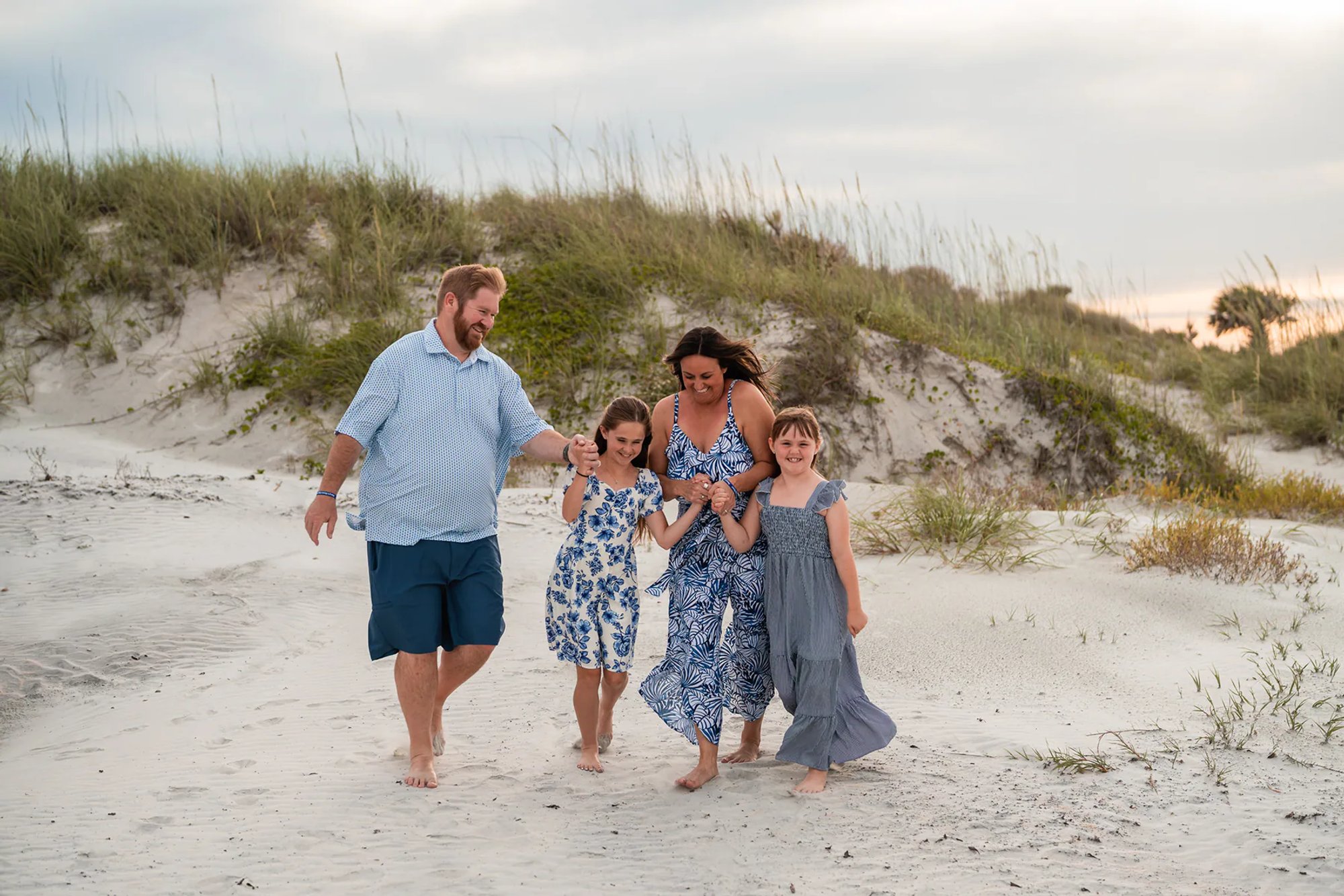Family laughing and walking through the sand during a relaxed beach photo session in Ponce Inlet.