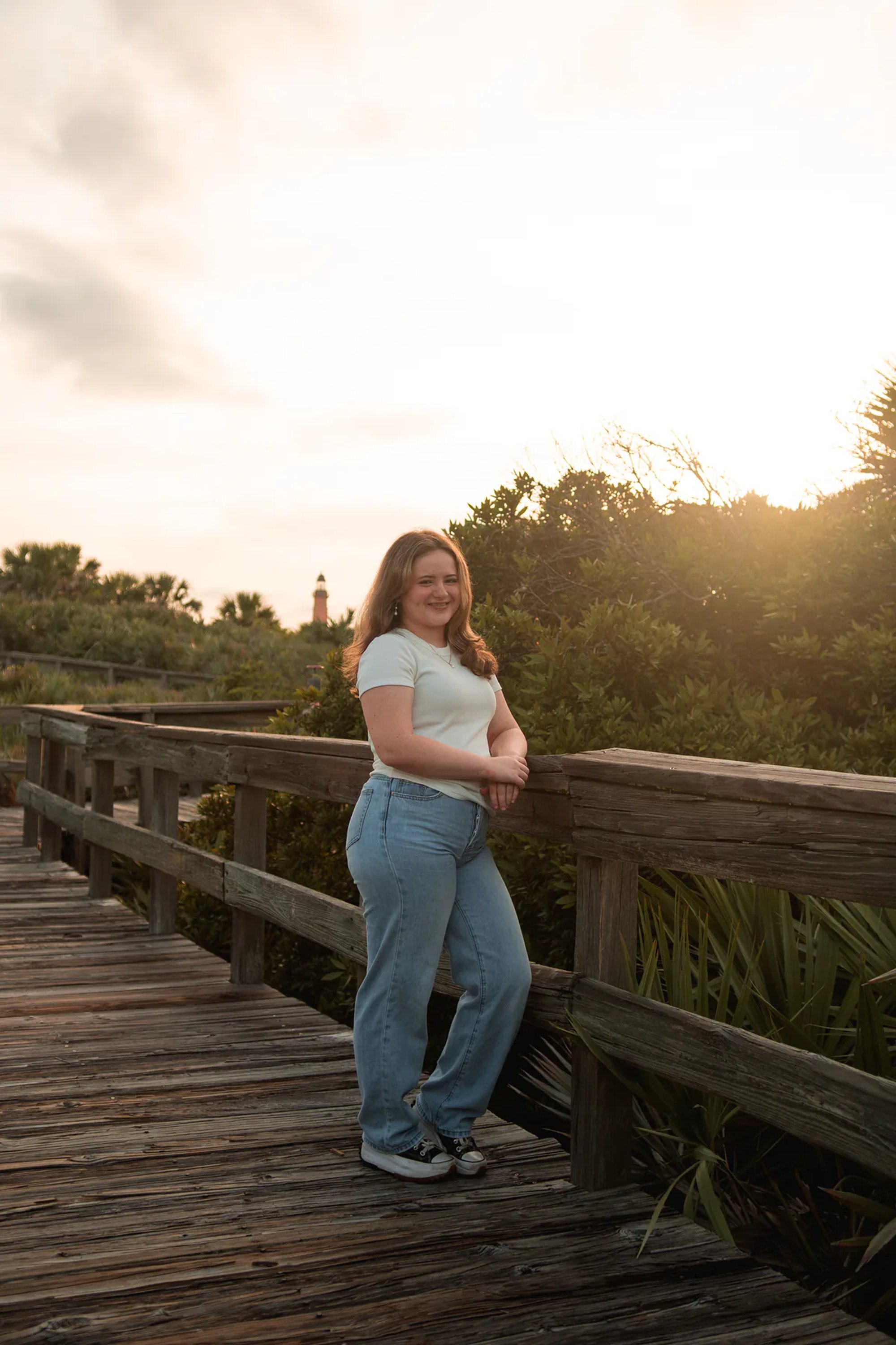 Daytona Beach area senior photos, Nelly standing on the wooden boardwalk in casual outfit, soft evening light behind her.