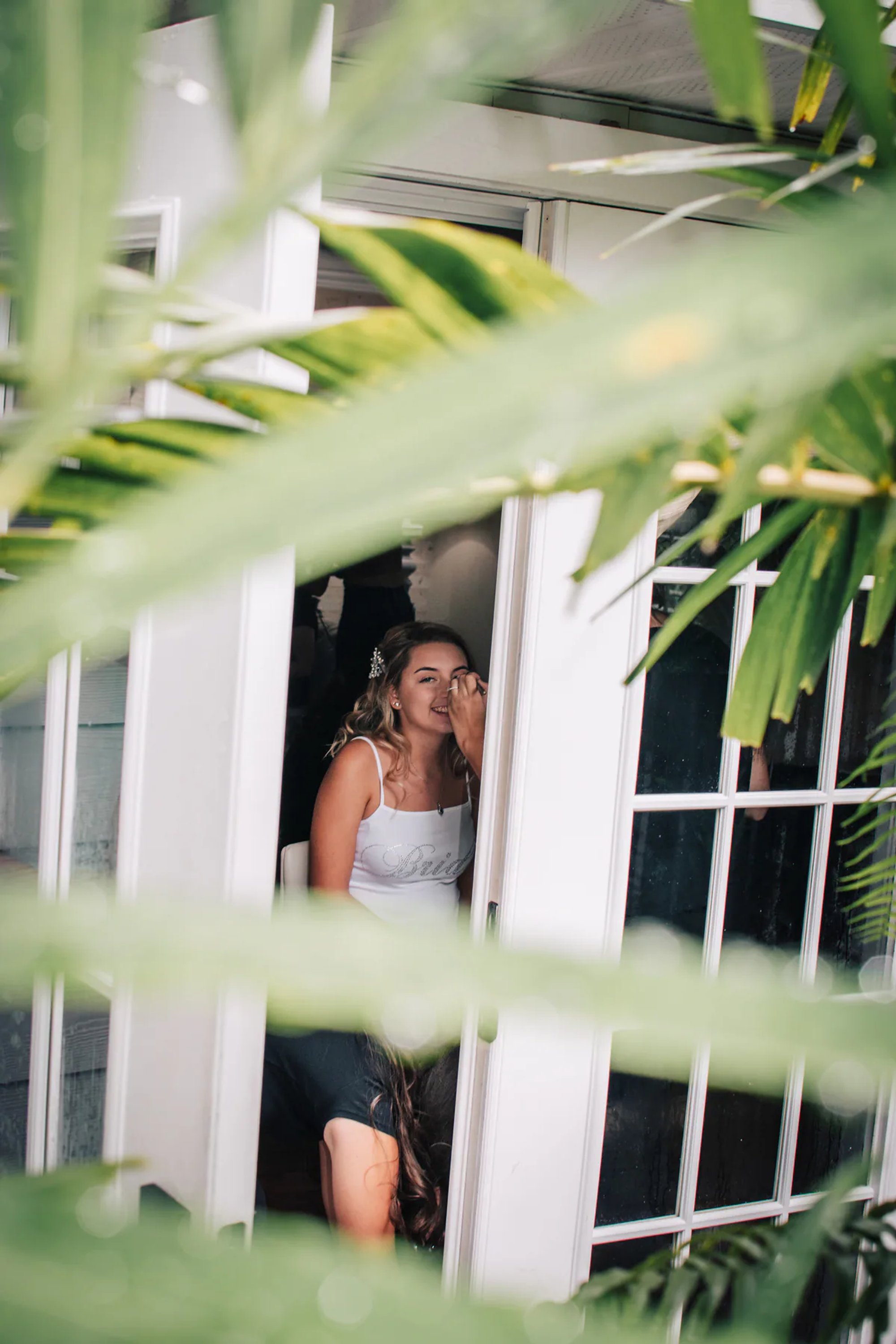 Bride and groom seen through soft green palm leaves.