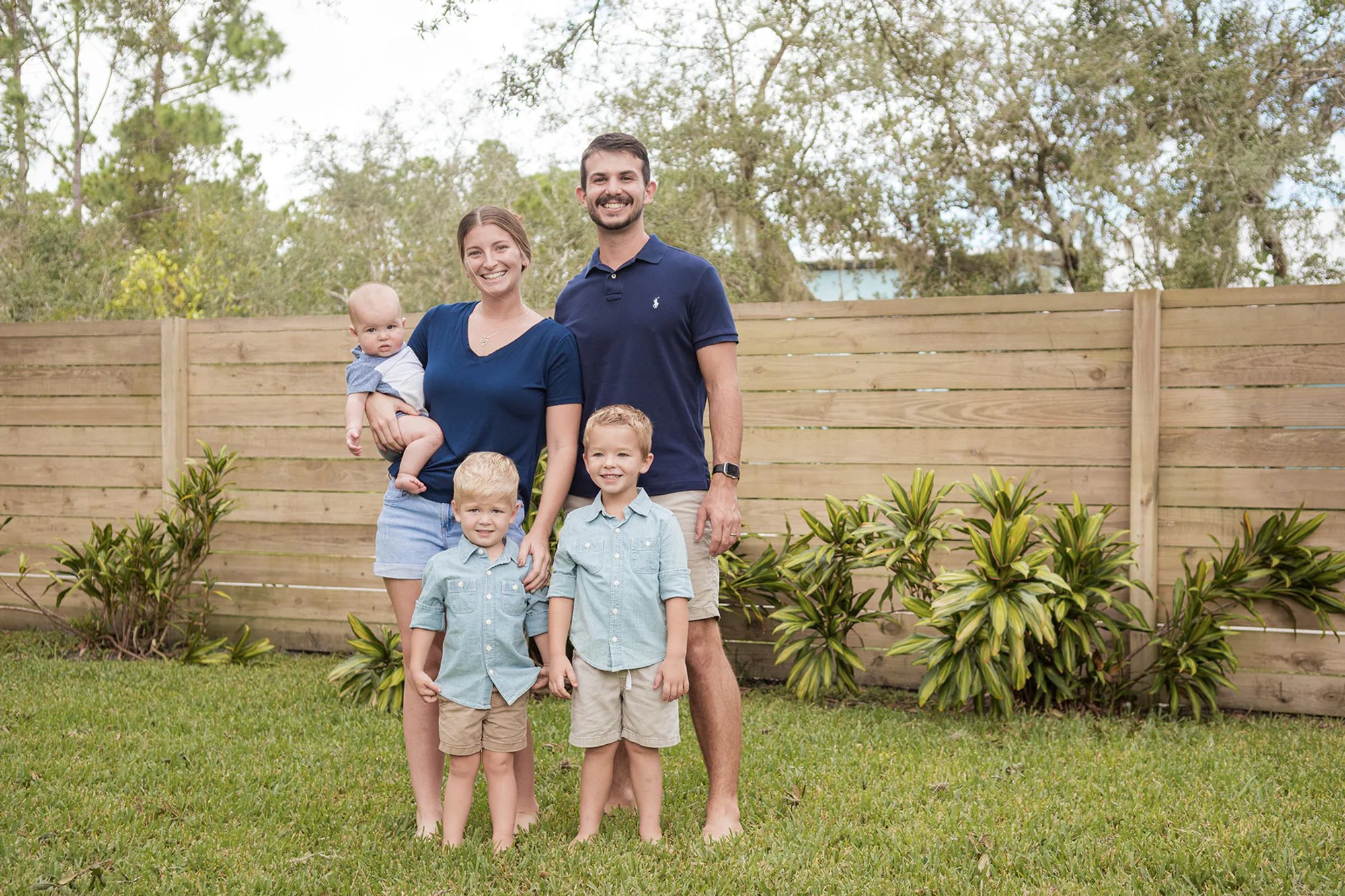 Parents and their young children standing together on a lawn.