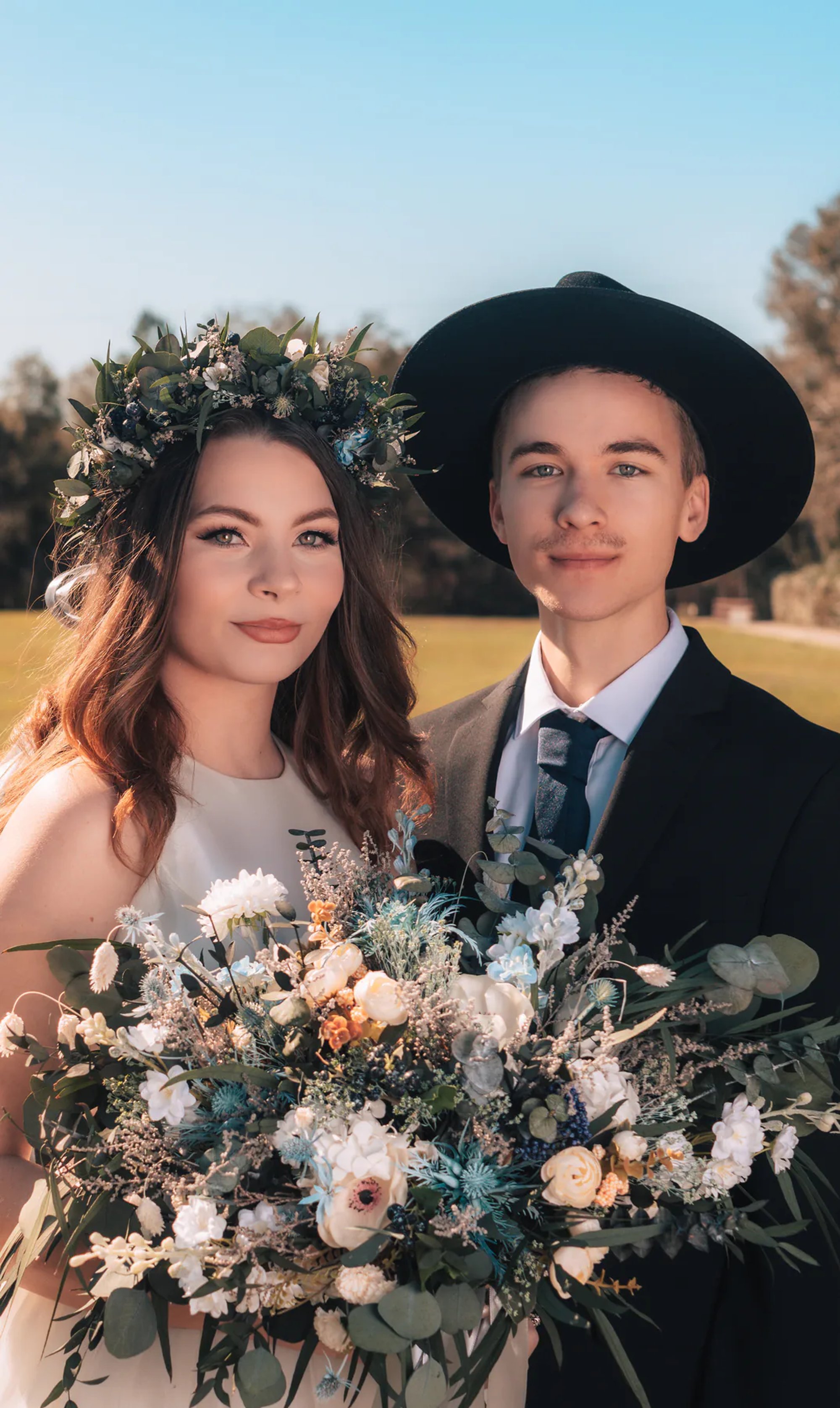 Bride and groom holding floral bouquets during an outdoor wedding portrait.