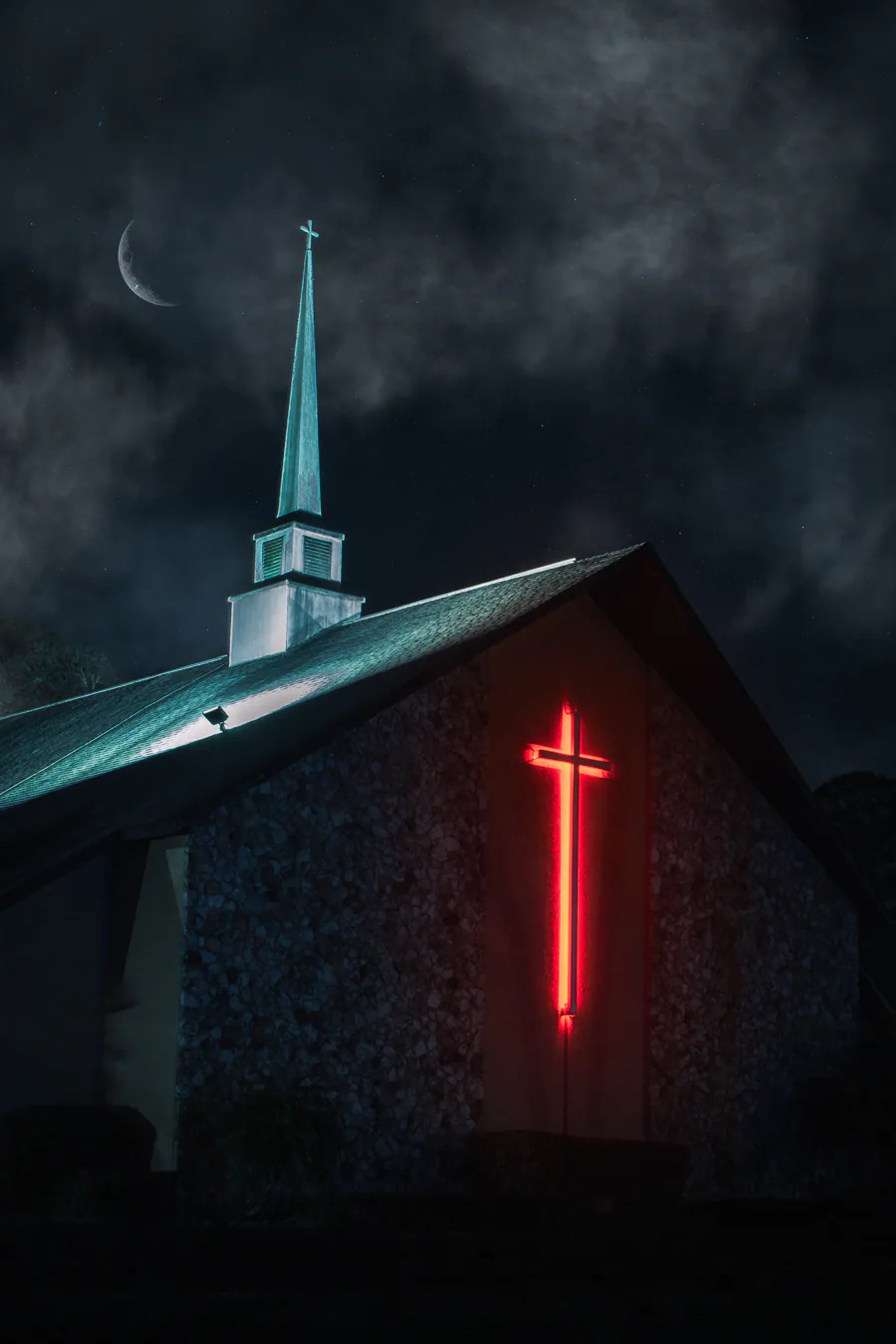 Church steeple and red illuminated cross beneath stormy clouds.