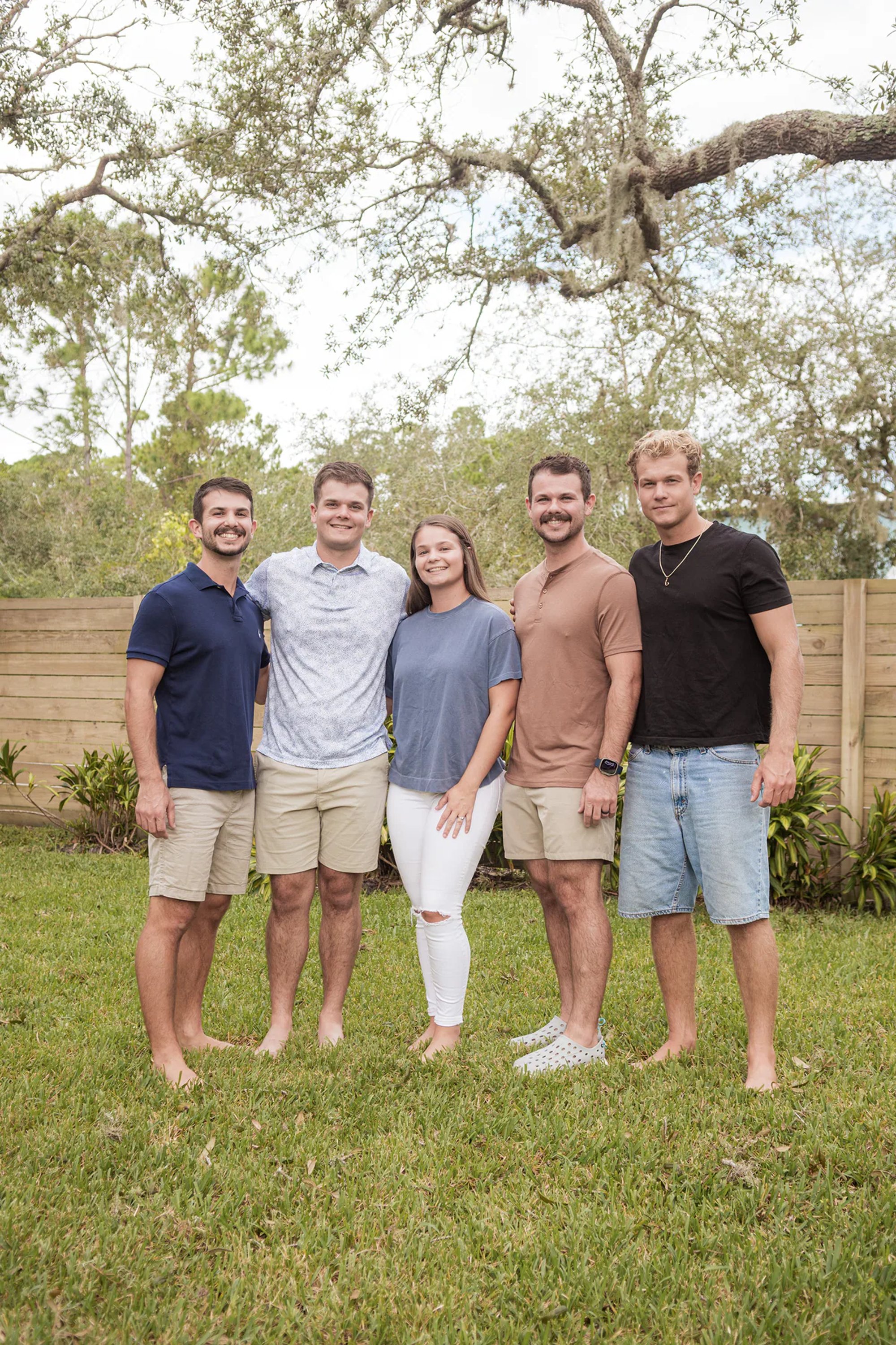 Four adult men standing together on a lawn.
