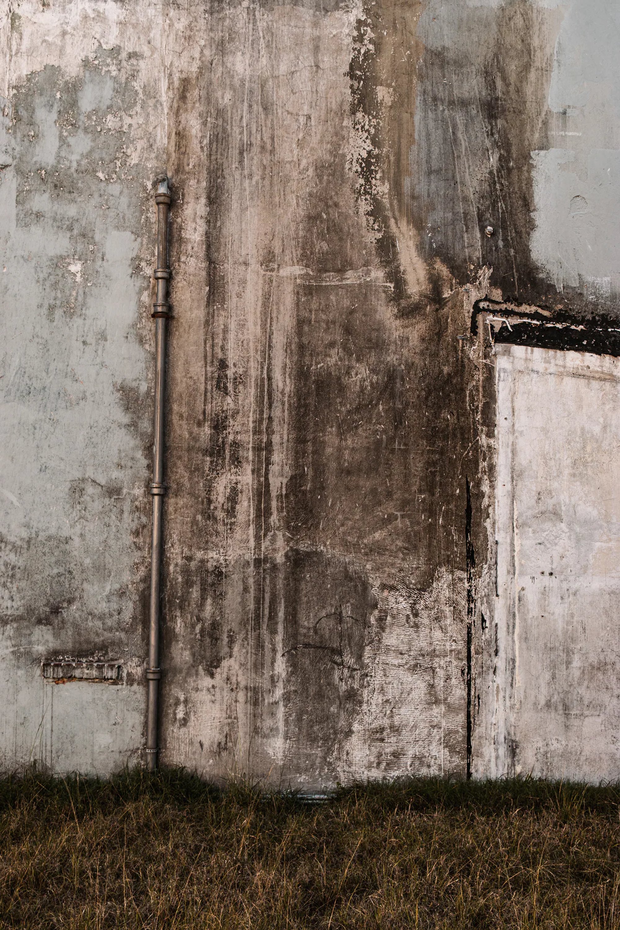 Weather-stained concrete wall with dark runoff marks.