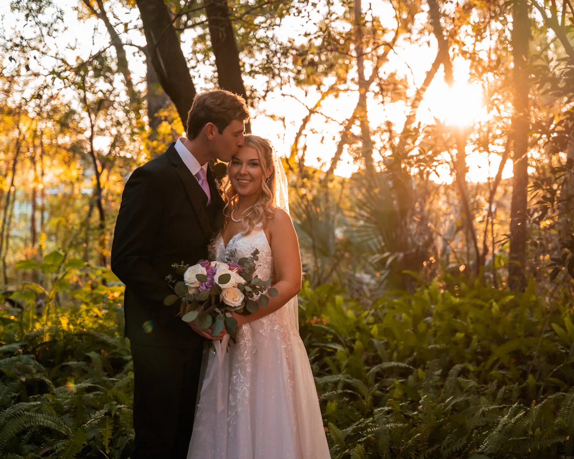 Groom kissing bride during sunset wedding portraits at Bridle Oaks Barn in DeLand Florida