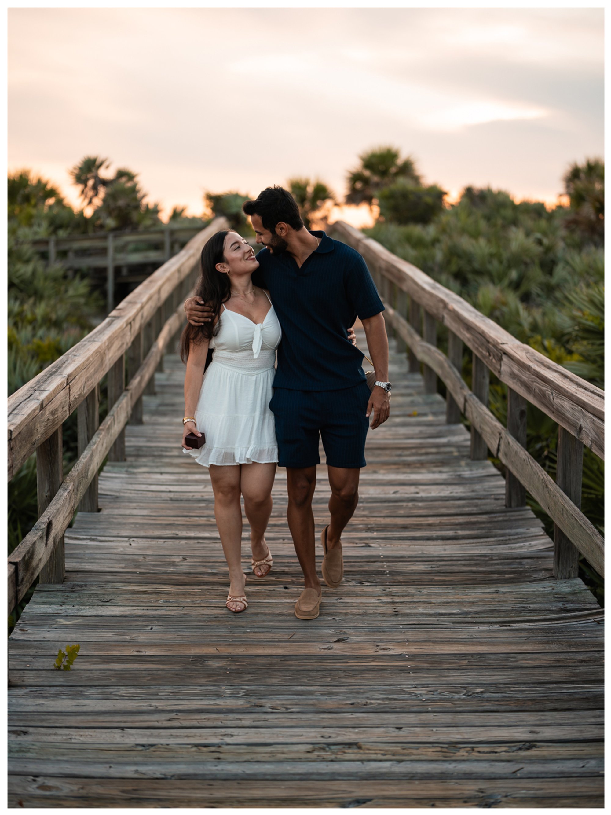 Dierick and Paulina walking together on the wooden boardwalk after their proposal.