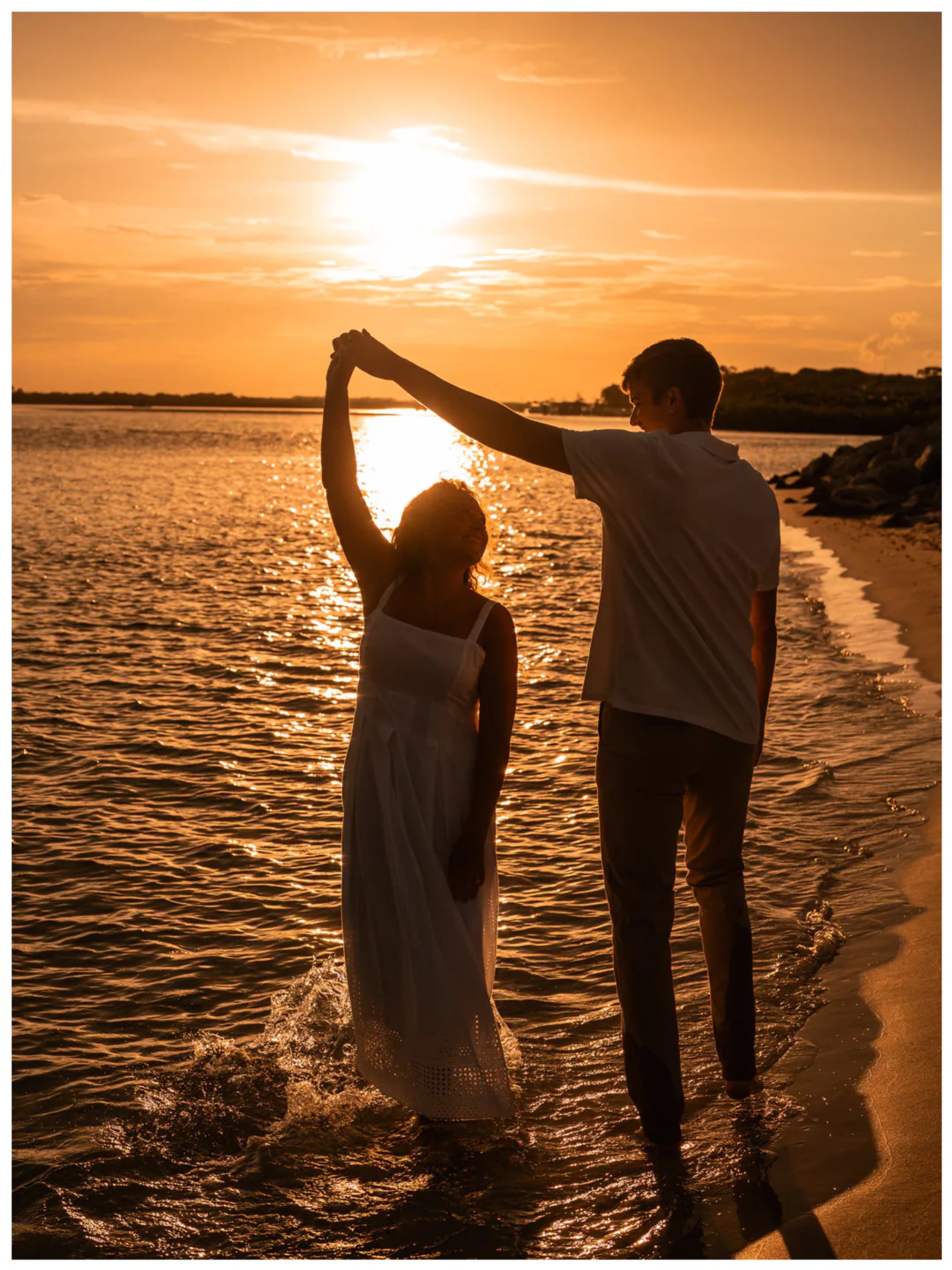 Couple twirling together along the golden shoreline.
