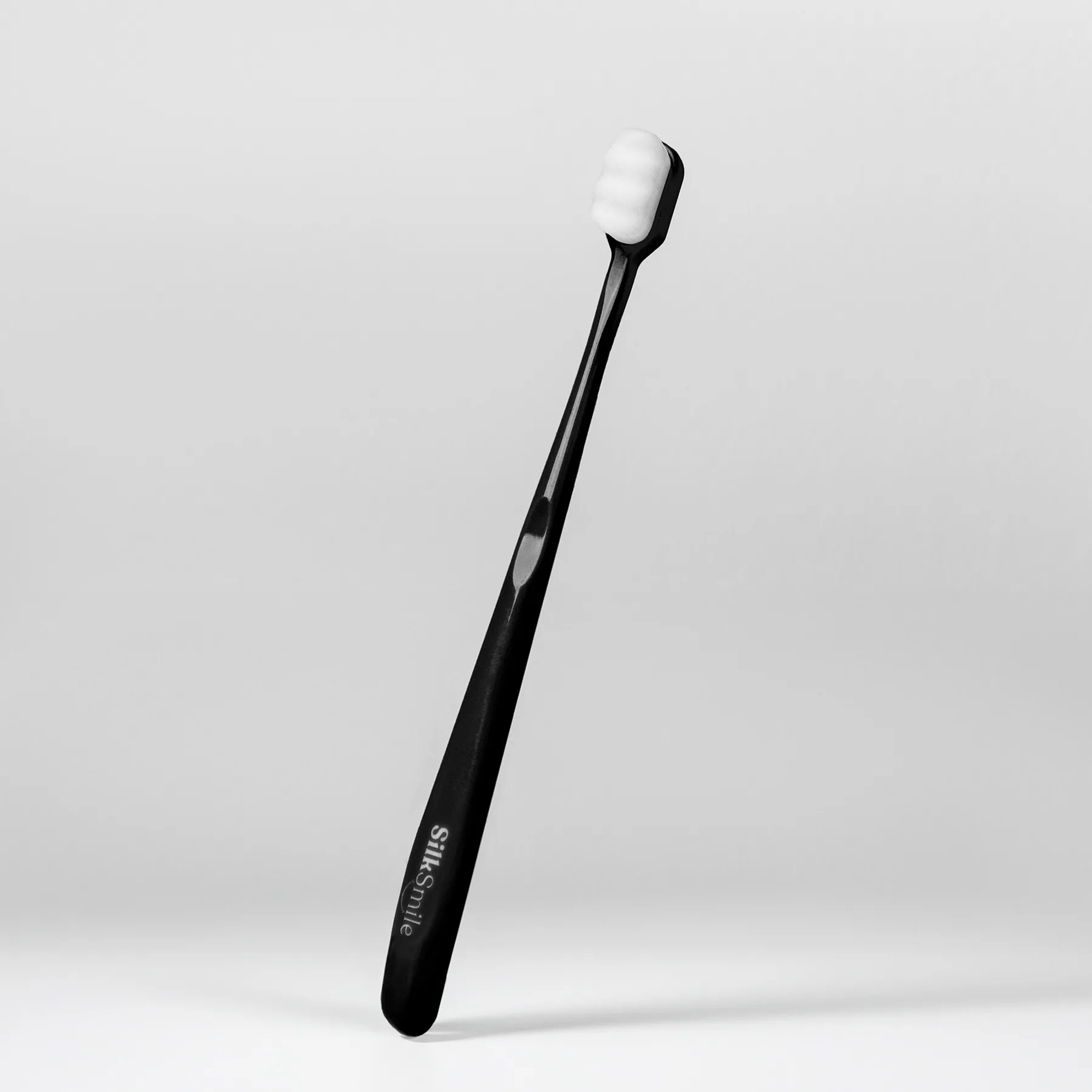 Slim black toothbrush standing against a white background.