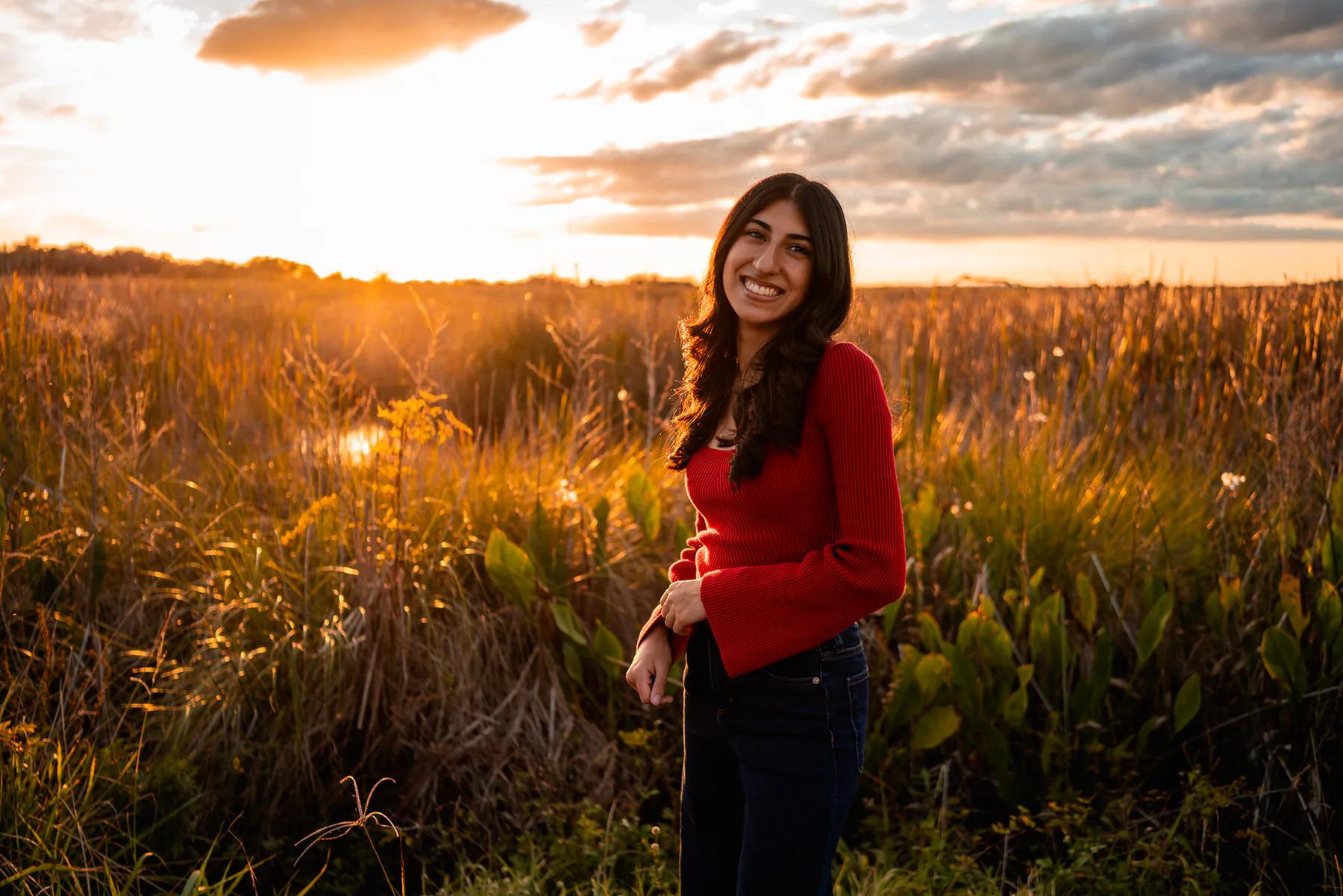 Ahaana standing in tall grass during senior photos at Lake Woodruff near DeLeon Springs