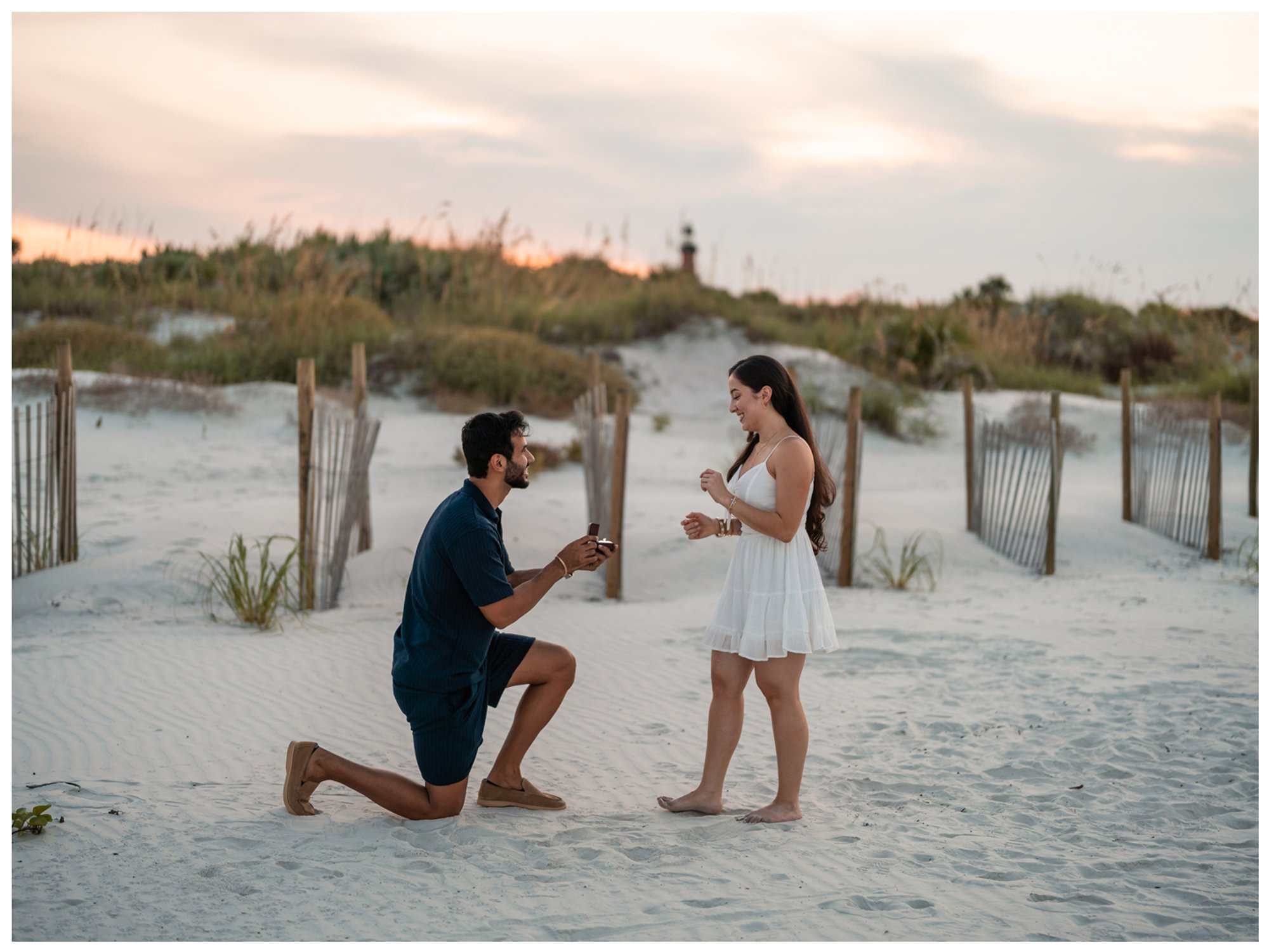 Dierick kneeling with an engagement ring as he surprises Paulina near the Lighthouse Point Park beach access in Ponce Inlet.