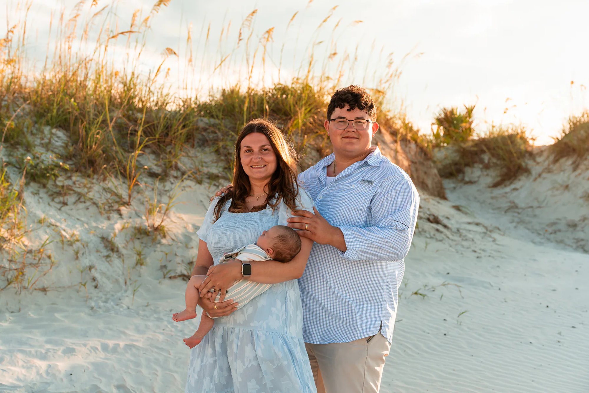 Parents holding their baby in the dunes during a Ponce Inlet Jetty Beach photo session.