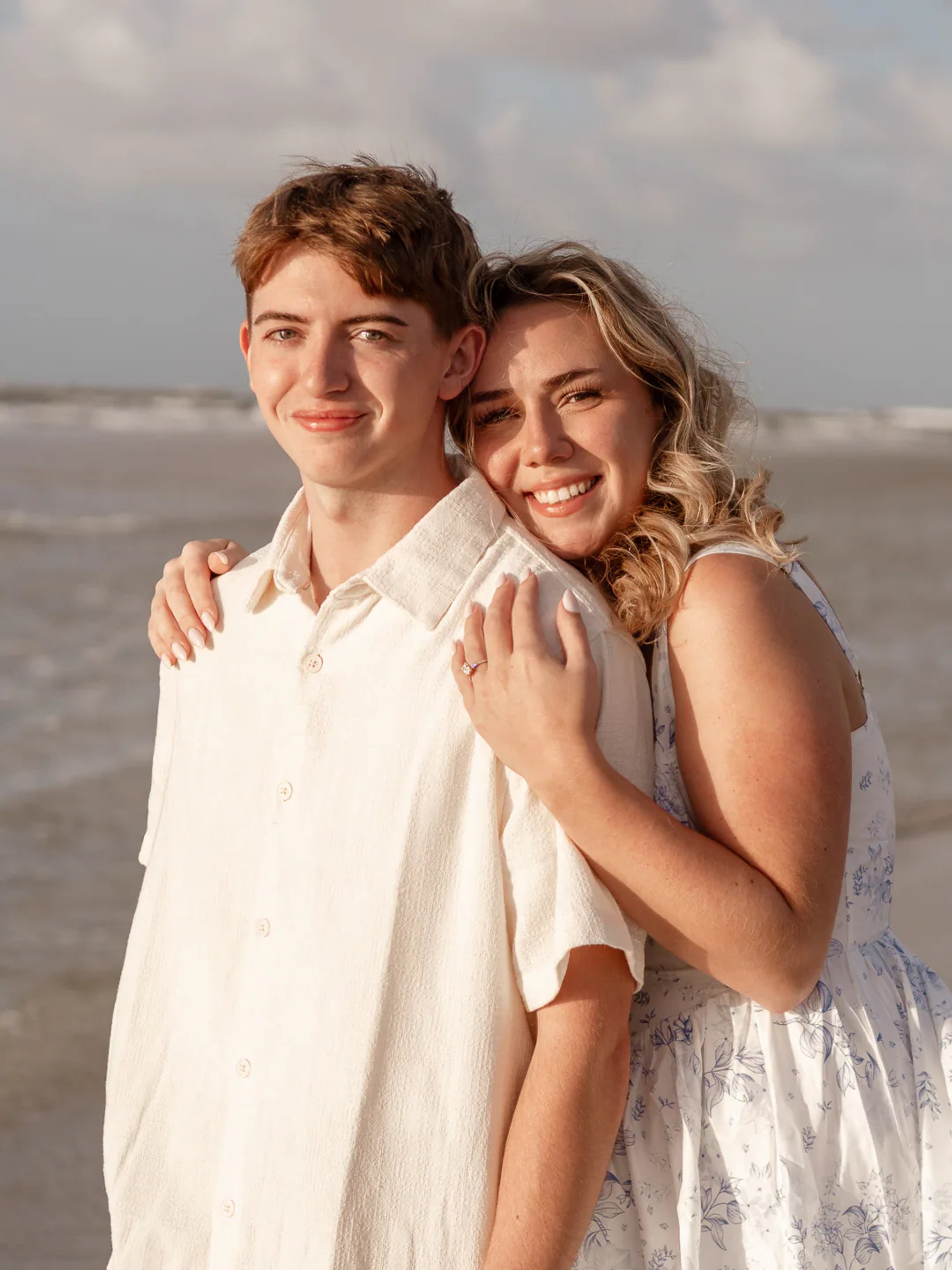 Couple standing close together during a beach engagement portrait.
