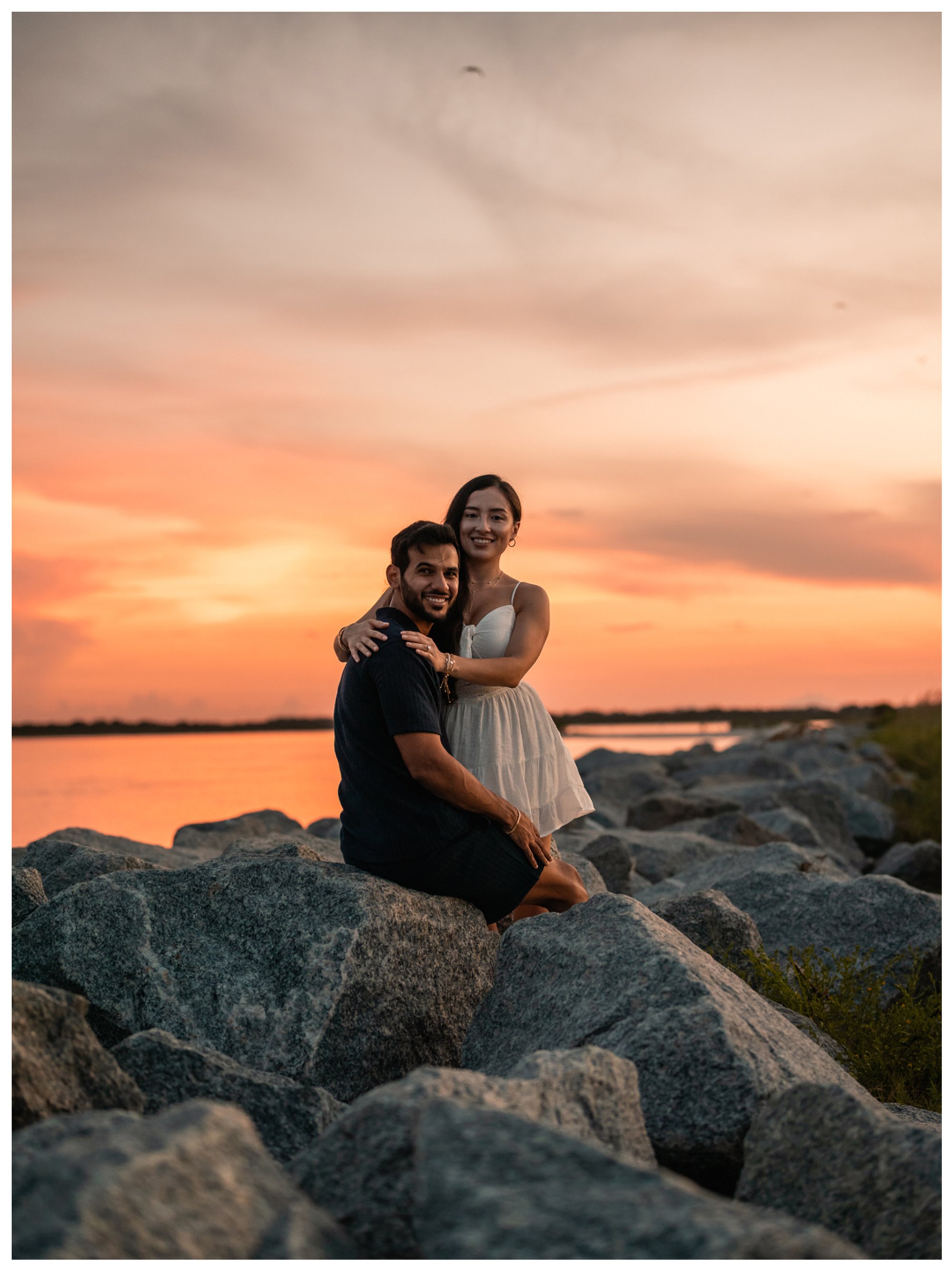 Dierick and Paulina posing on the inlet rocks as the evening sky glows orange.