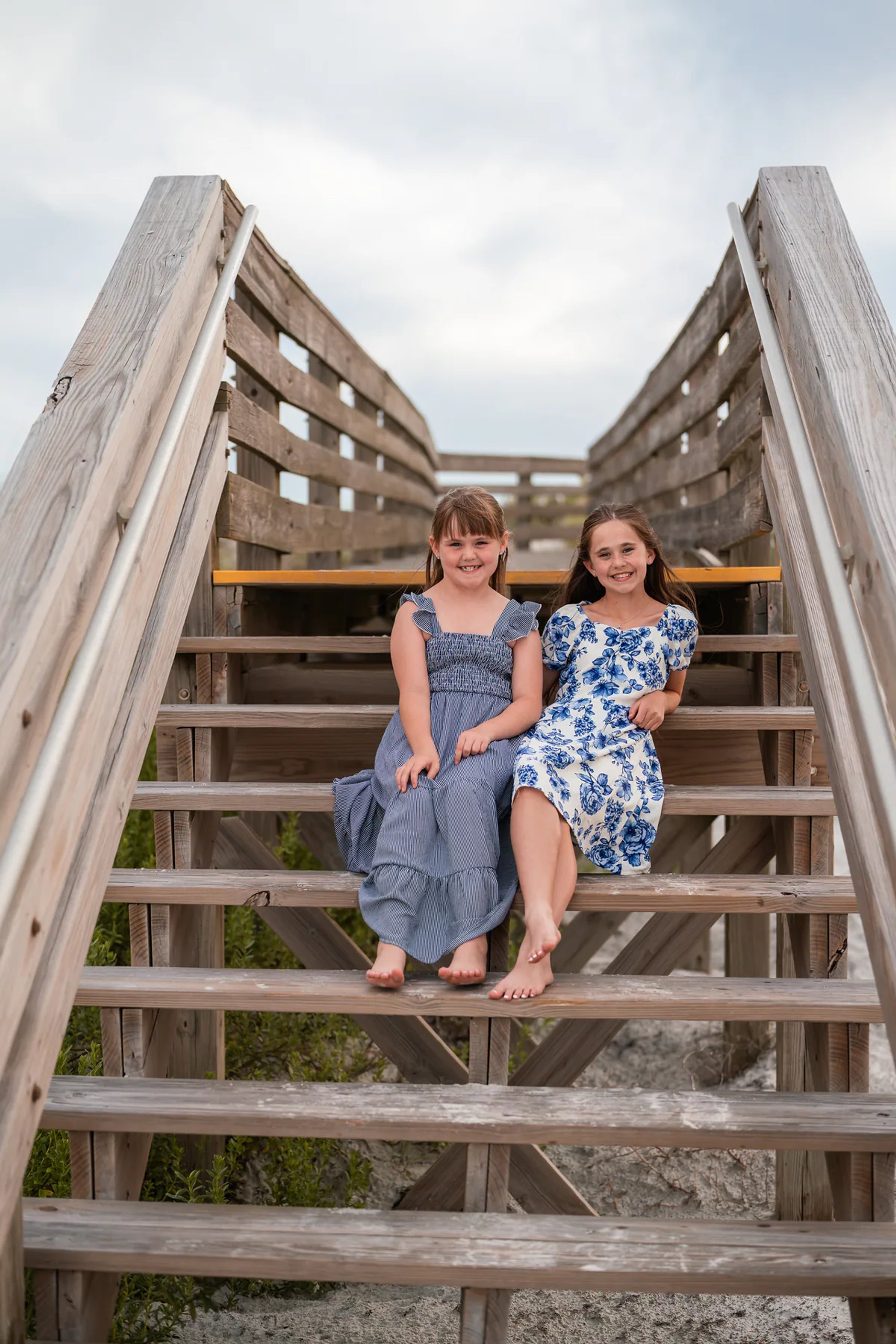 Two girls sitting on the beach access stairs during a family photography session in Ponce Inlet.