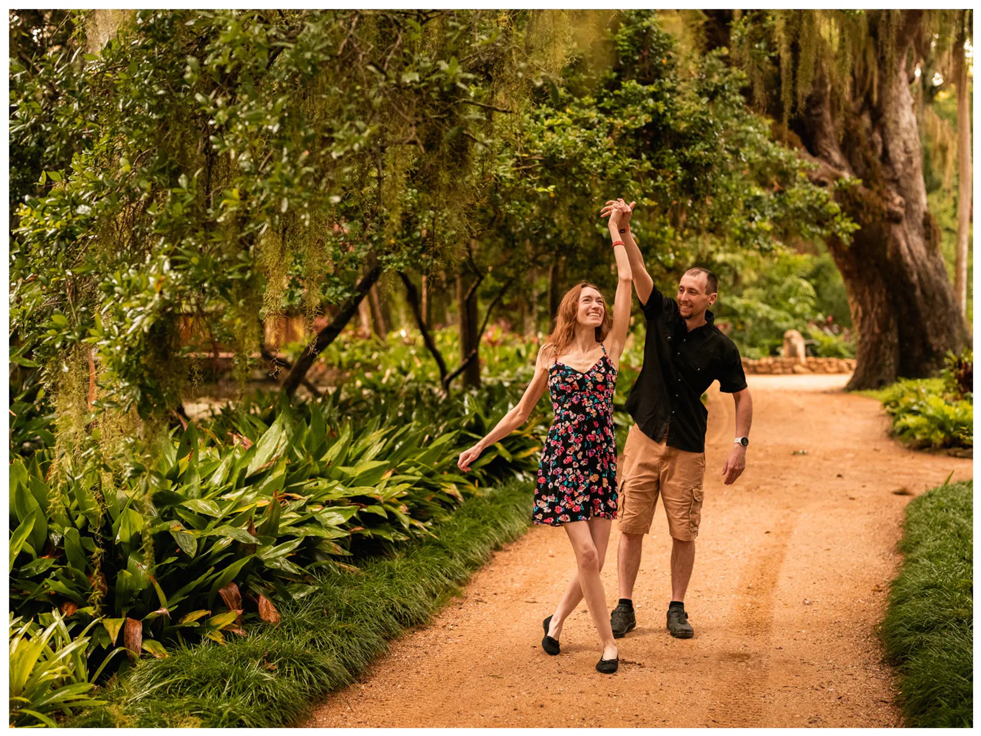 Couple walking hand in hand along a garden path during a Washington Oaks couples photo session.
