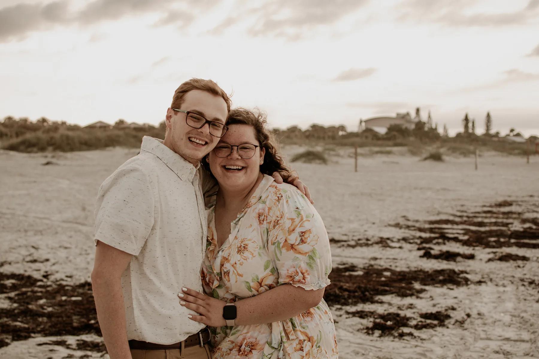 Smiling couple embracing on a sandy beach.