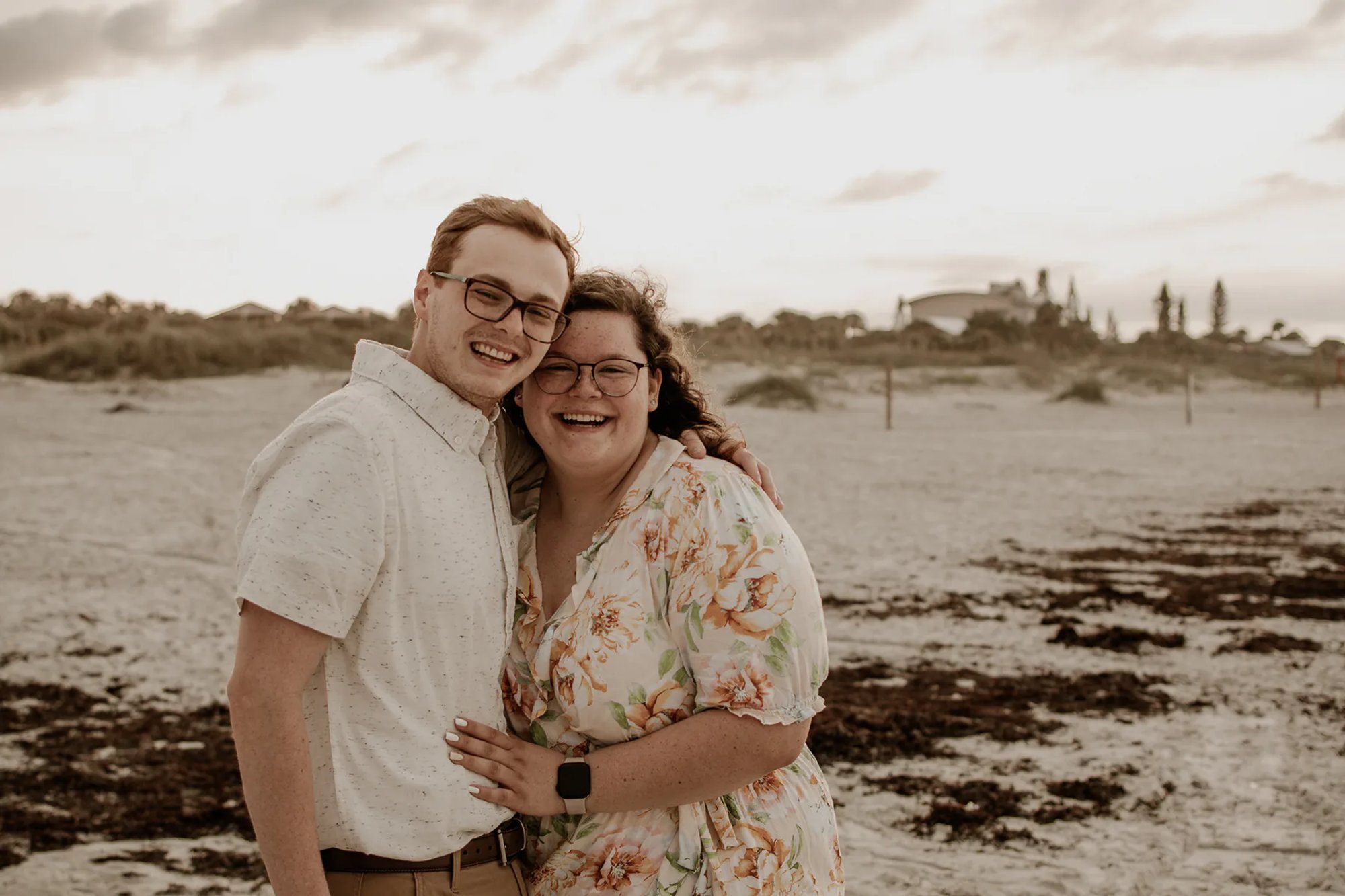 Smiling couple embracing on a sandy beach.