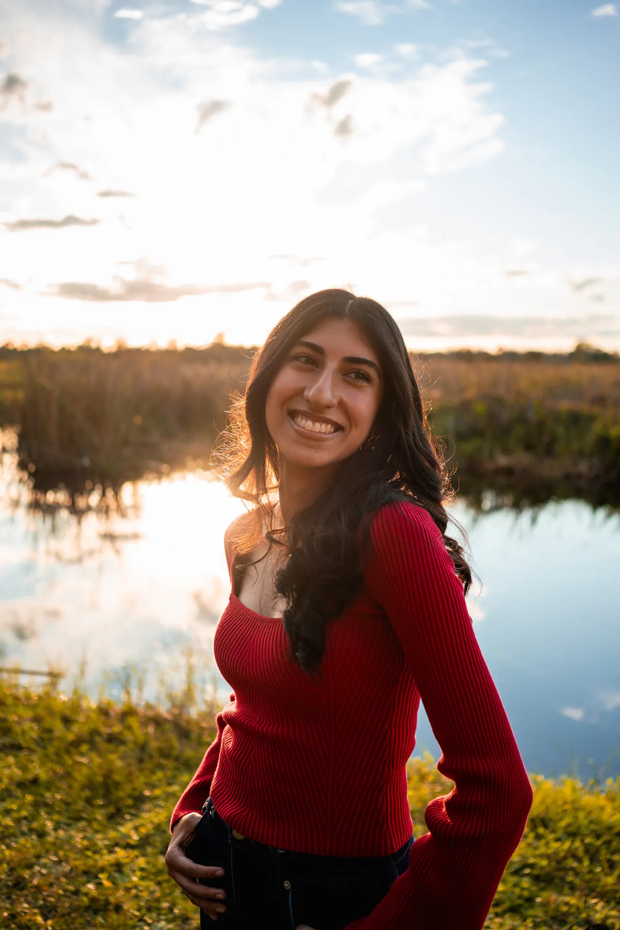Ahaana smiling by the water for Lake Woodruff senior portraits in Volusia County