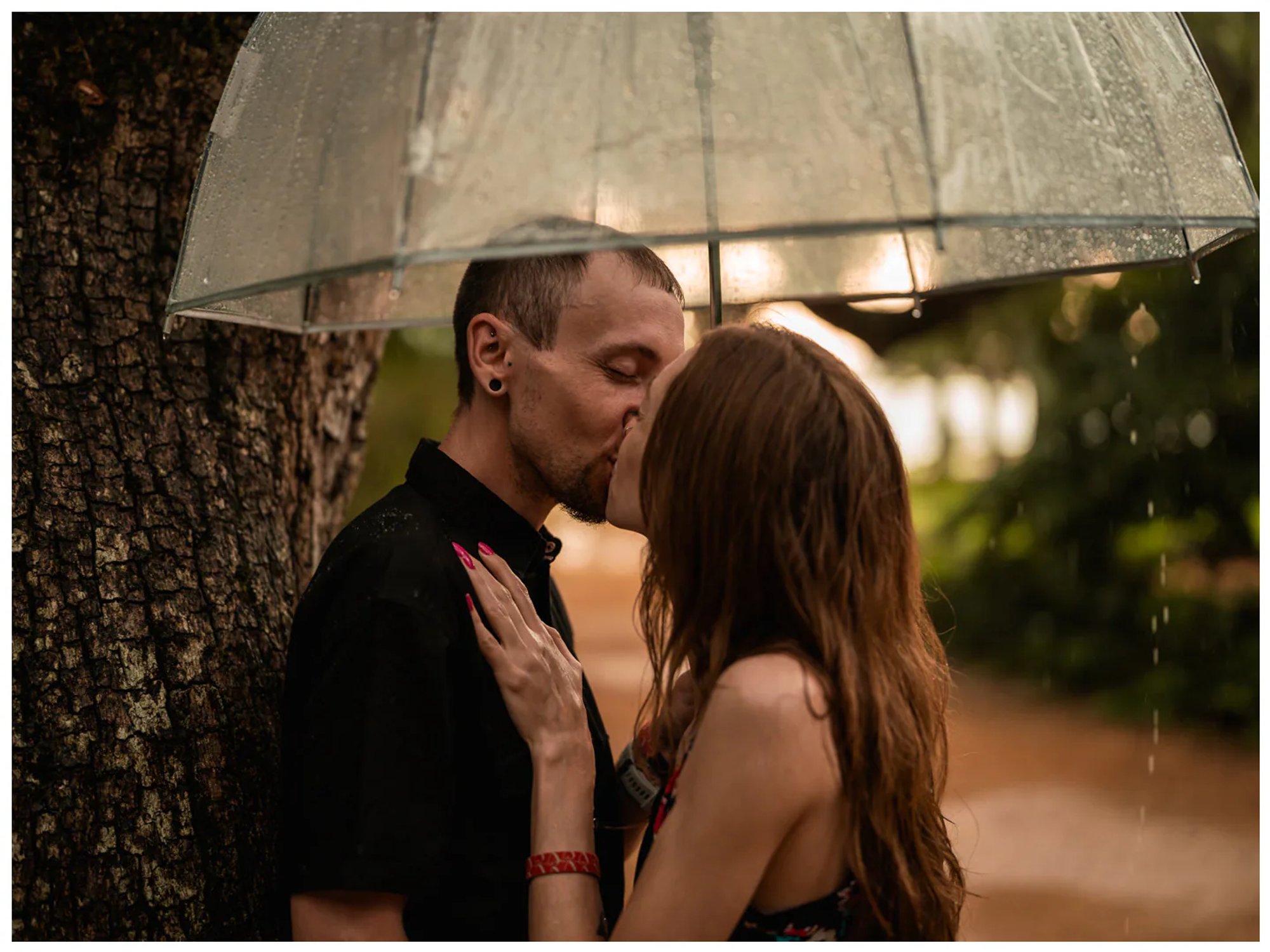 Close-up of a couple kissing beneath a transparent umbrella beside an oak tree at Washington Oaks.