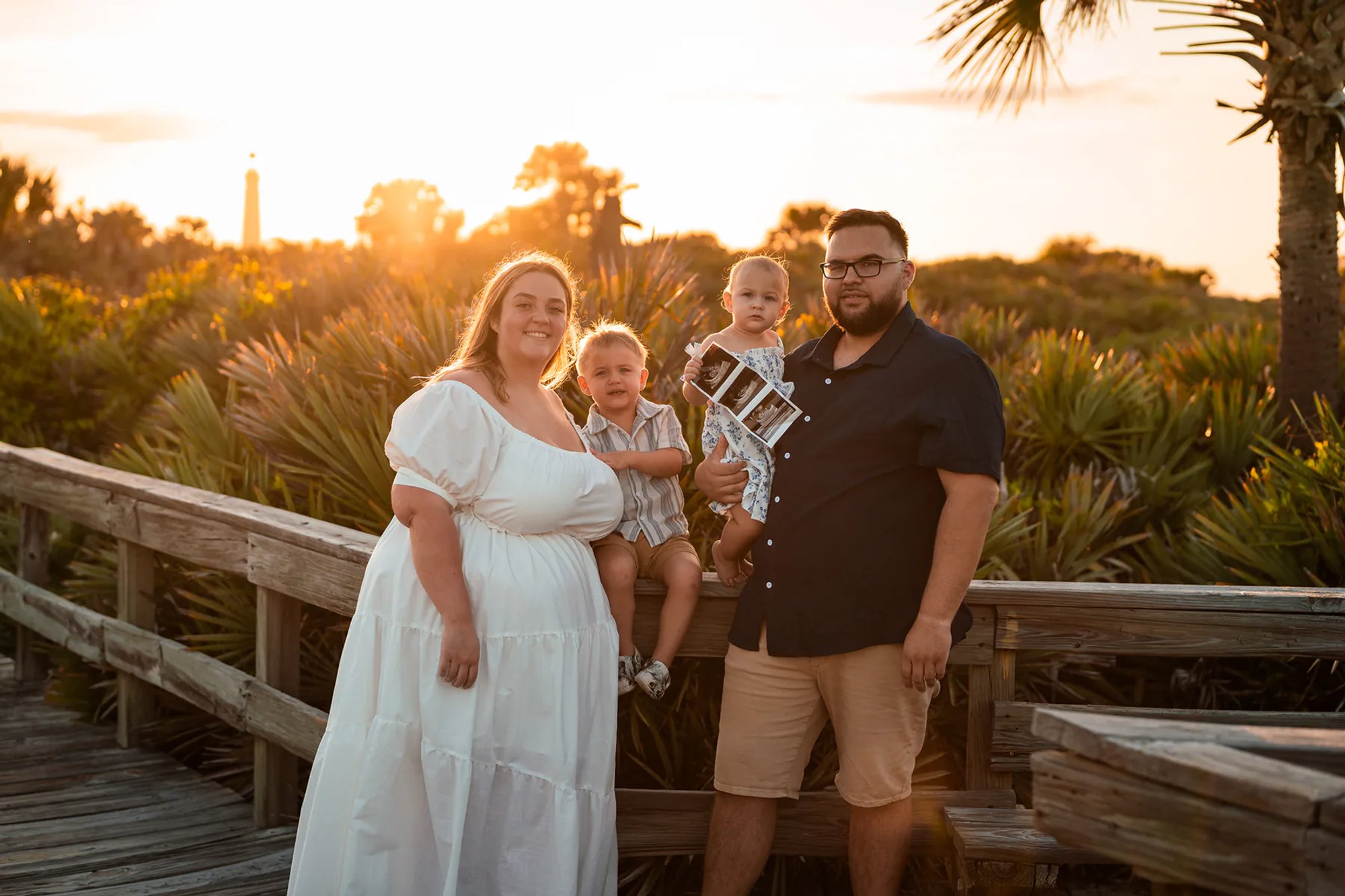 Ponce Inlet family photos on boardwalk with parents and children at sunset in Florida