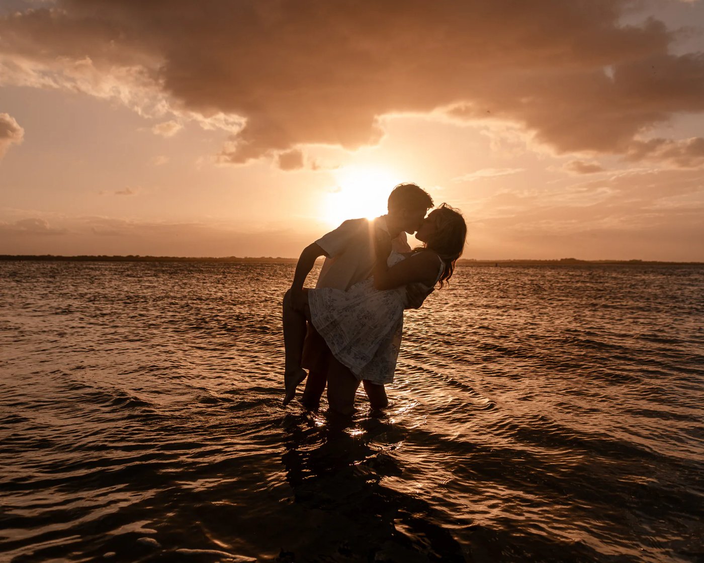 Joey and Lexi sharing a sunset moment in the water after their beach proposal in New Smyrna Beach.