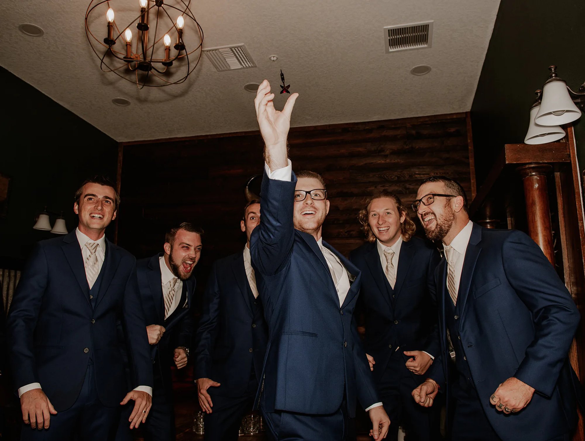 Groom and groomsmen in navy suits celebrating before wedding ceremony, candid group photo at Florida wedding venue.