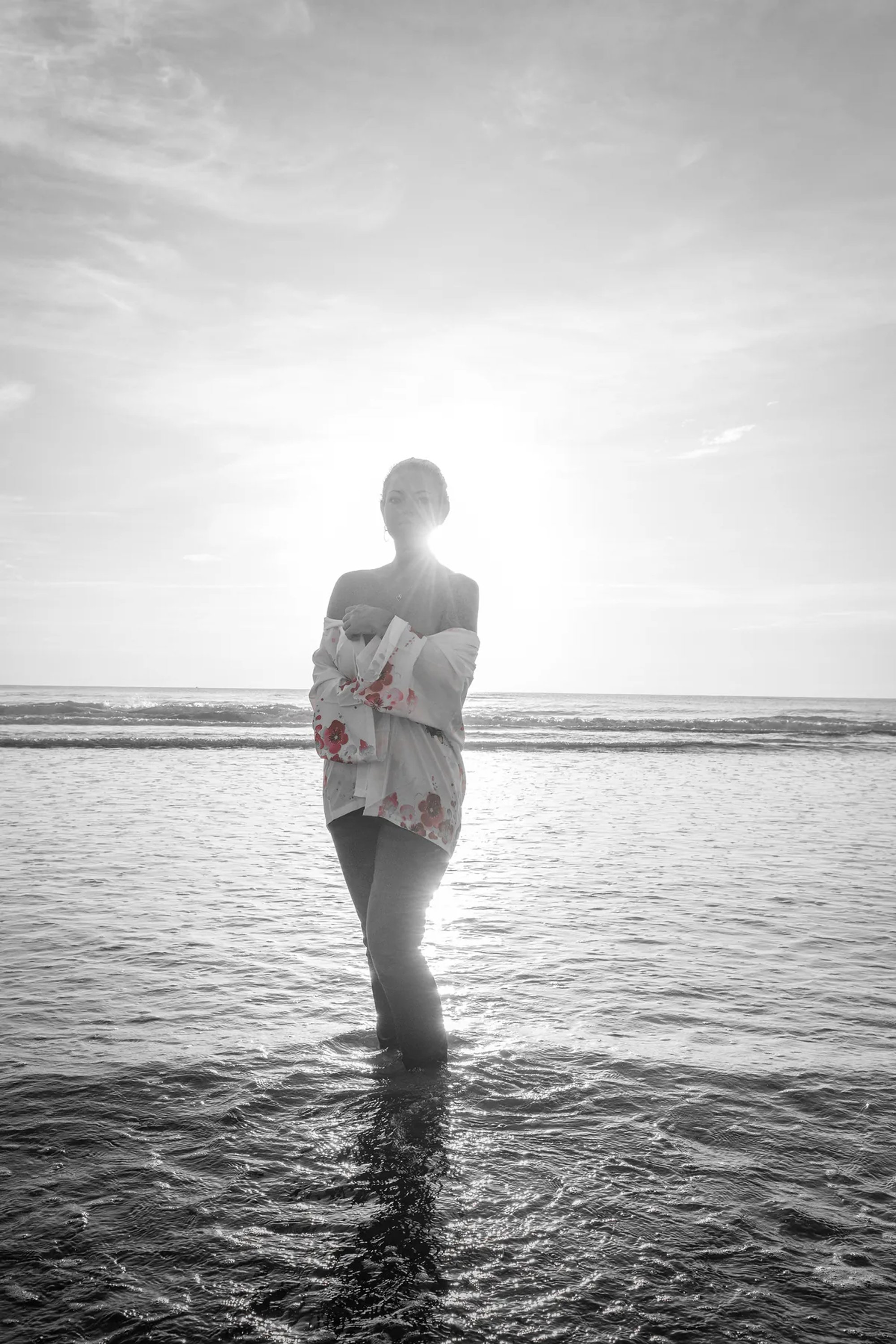 Black-and-white portrait of a woman standing in shallow ocean water.