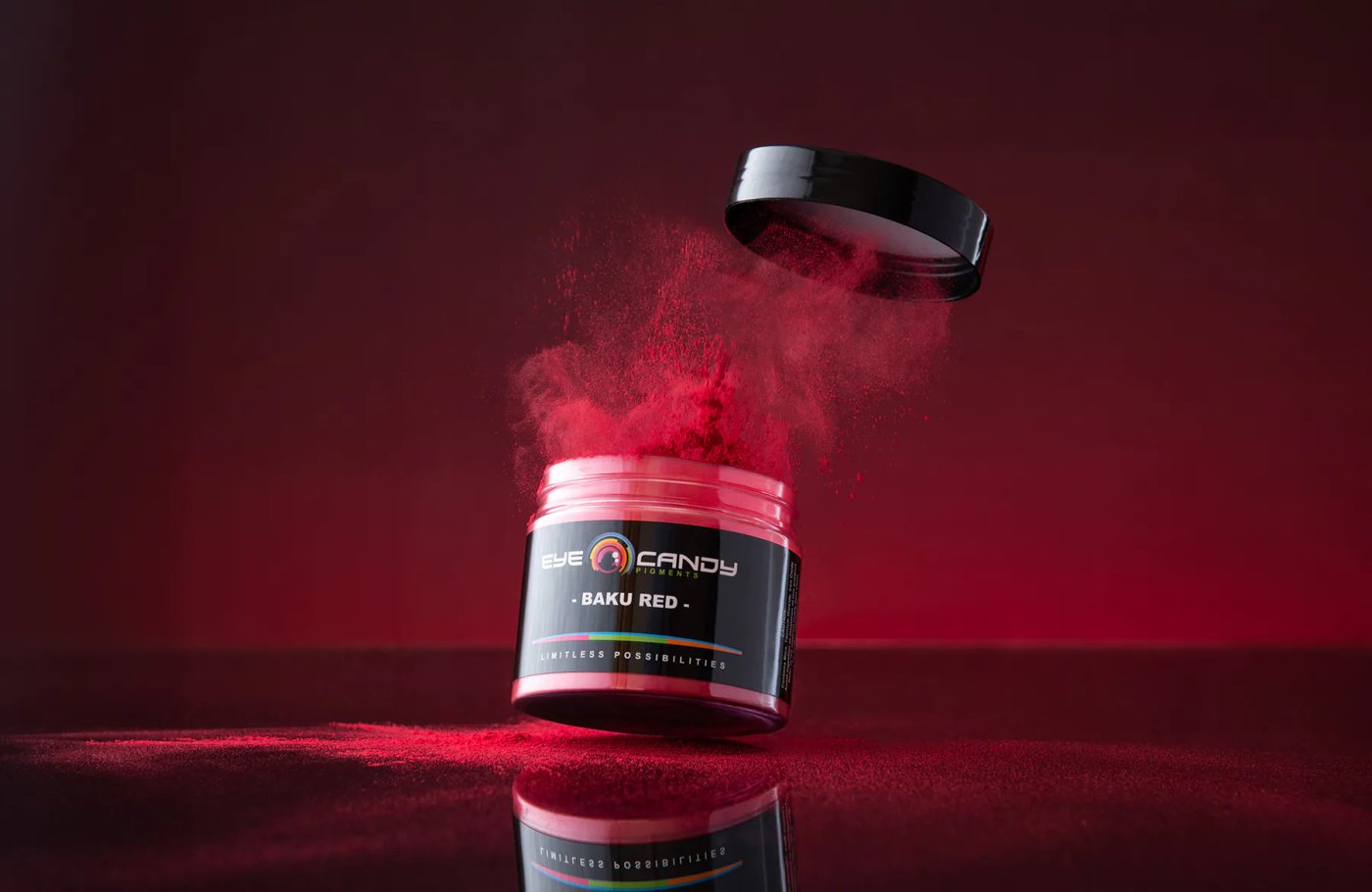 Eye Candy Pigments jar with red powder suspended above it on a red background.