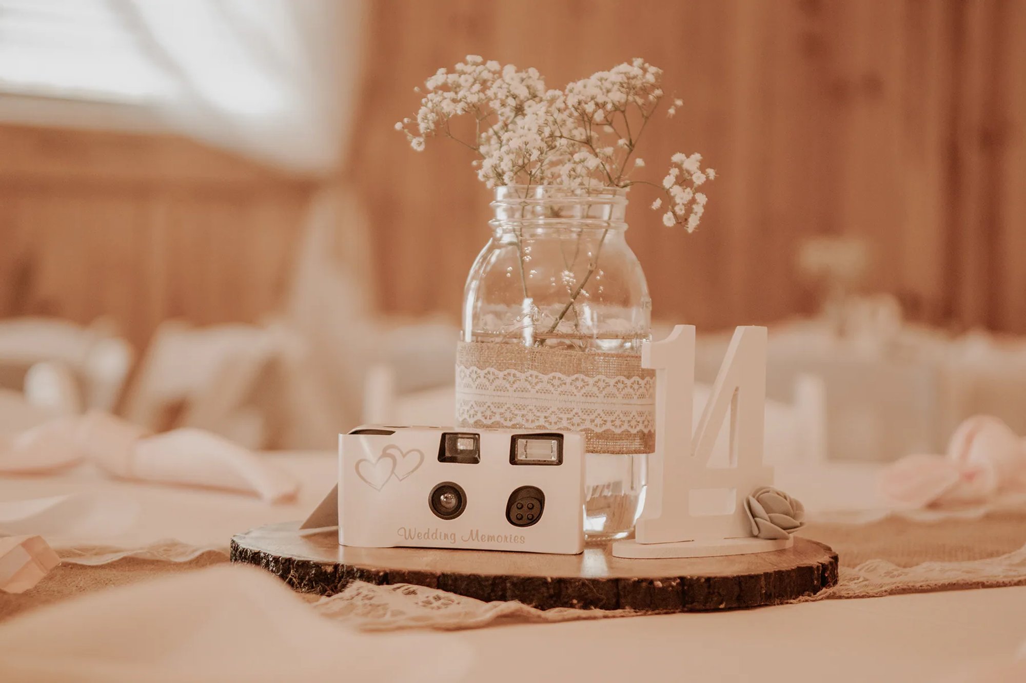 Mason jar with baby's breath and an instant camera on a rustic reception table.