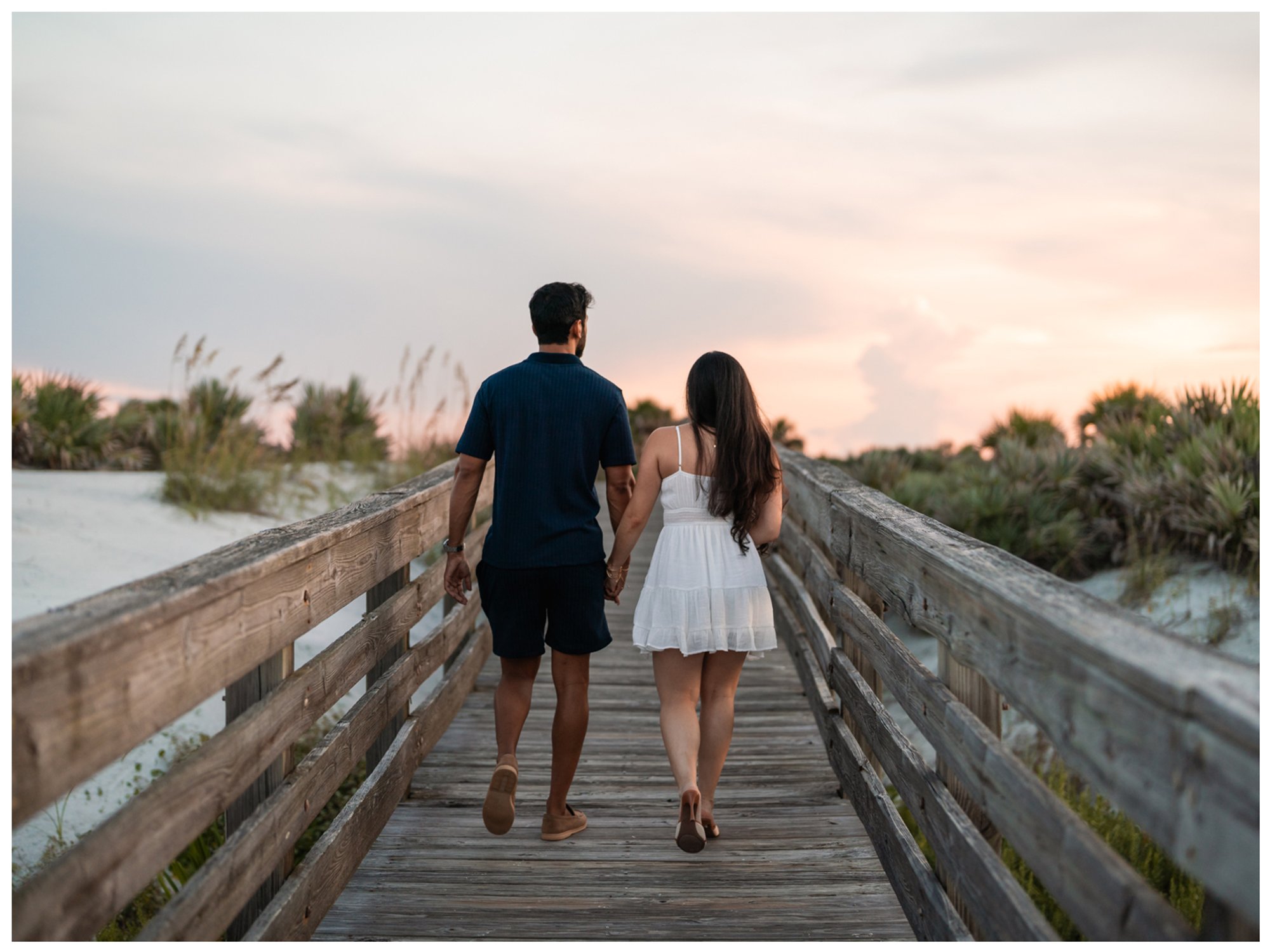 Rear view of Dierick and Paulina walking toward the beach on the Lighthouse Point Park boardwalk.
