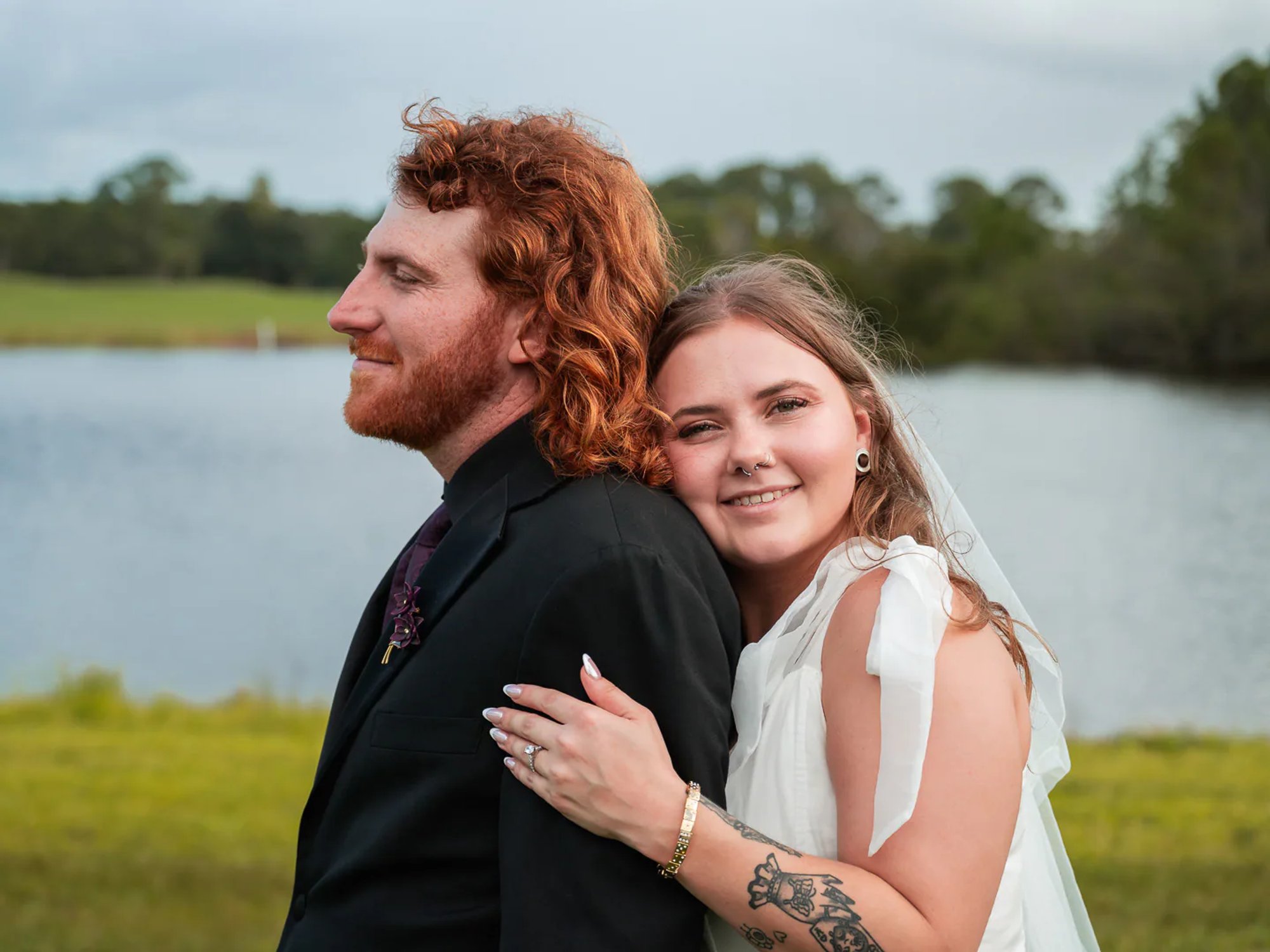Bride embracing the groom during a lakeside wedding portrait.
