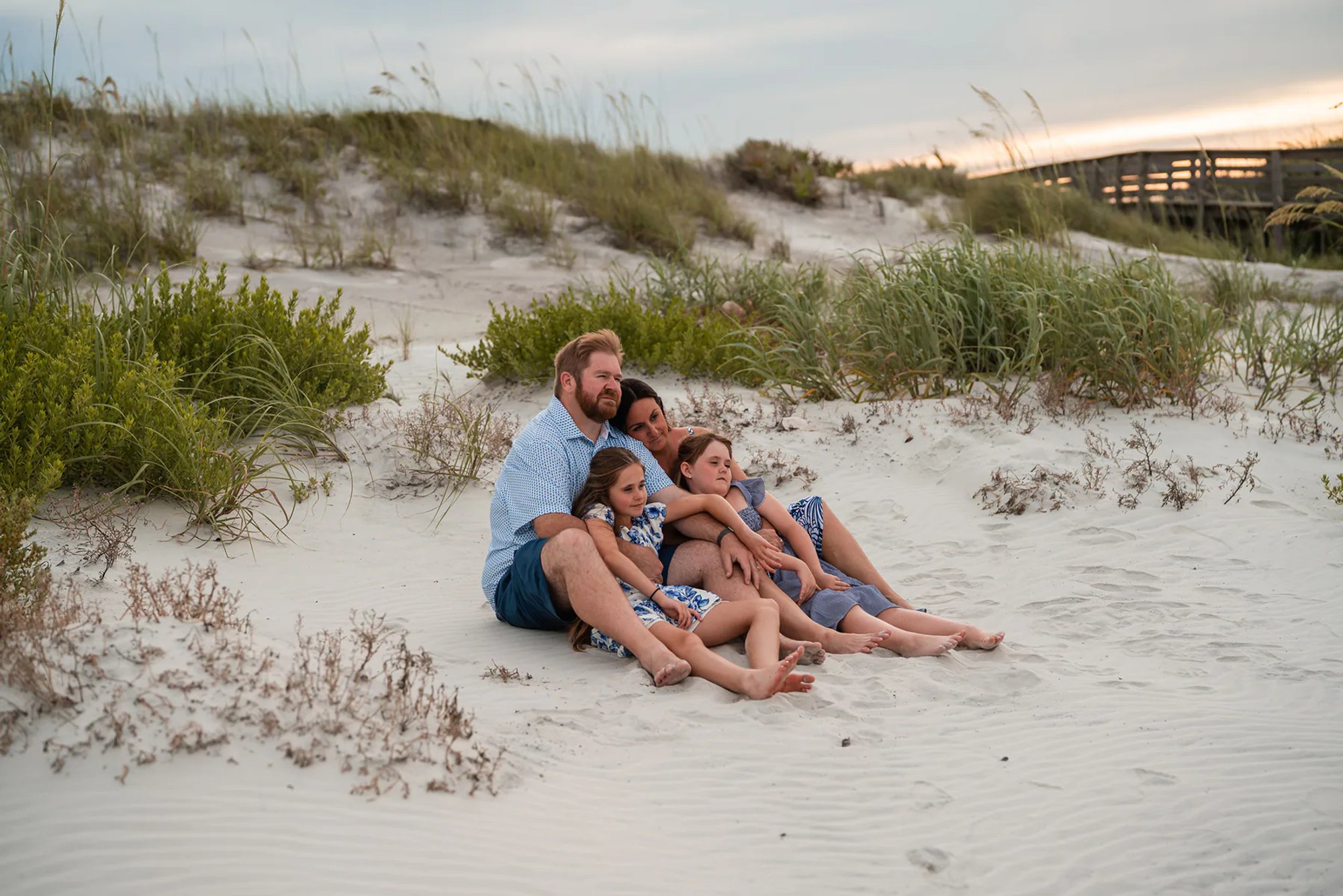 Family sitting together in the dunes during a relaxed beach photo session in Ponce Inlet.