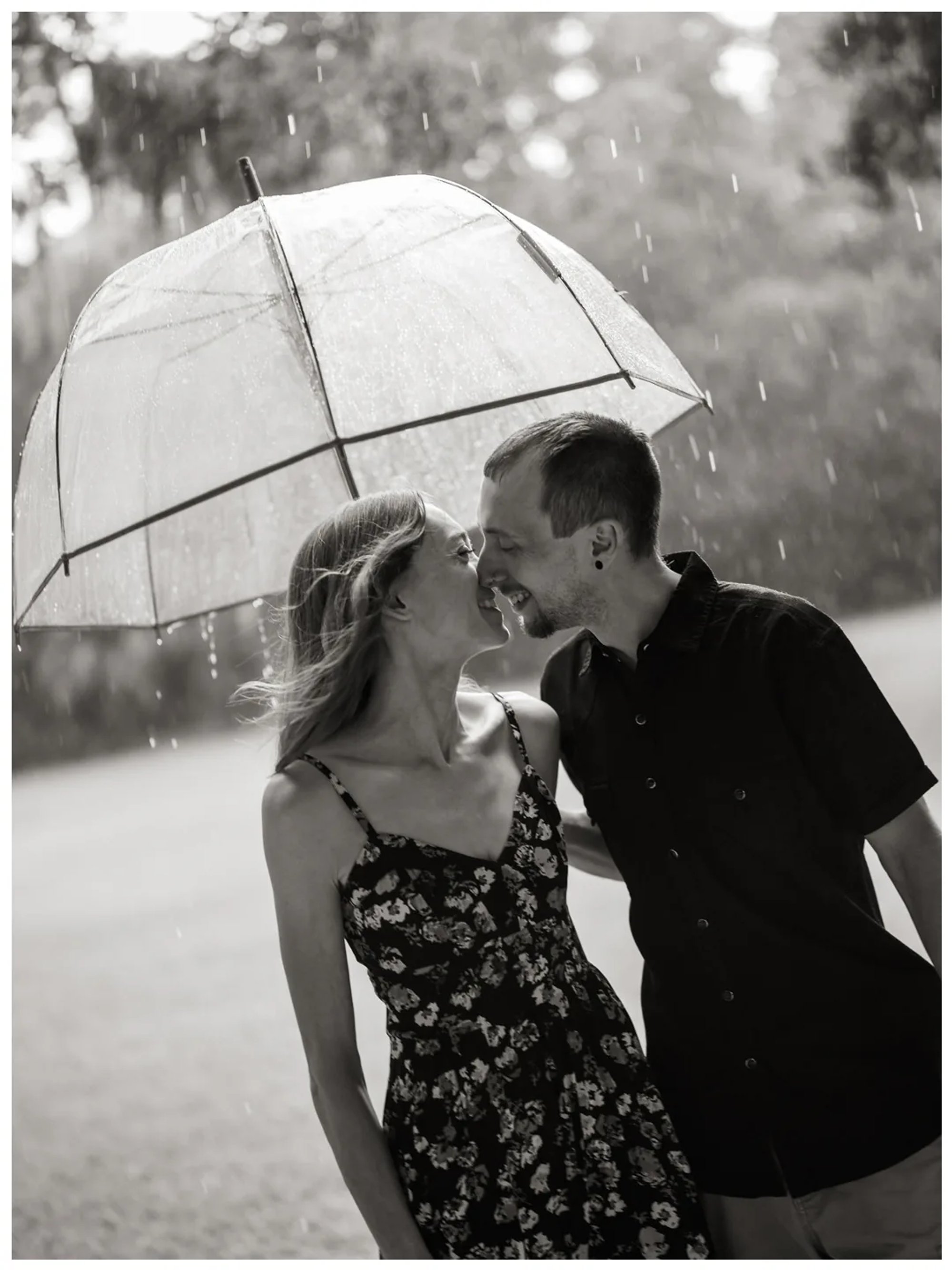 Black-and-white photo of a couple laughing under a clear umbrella in the rain at Washington Oaks Gardens State Park.