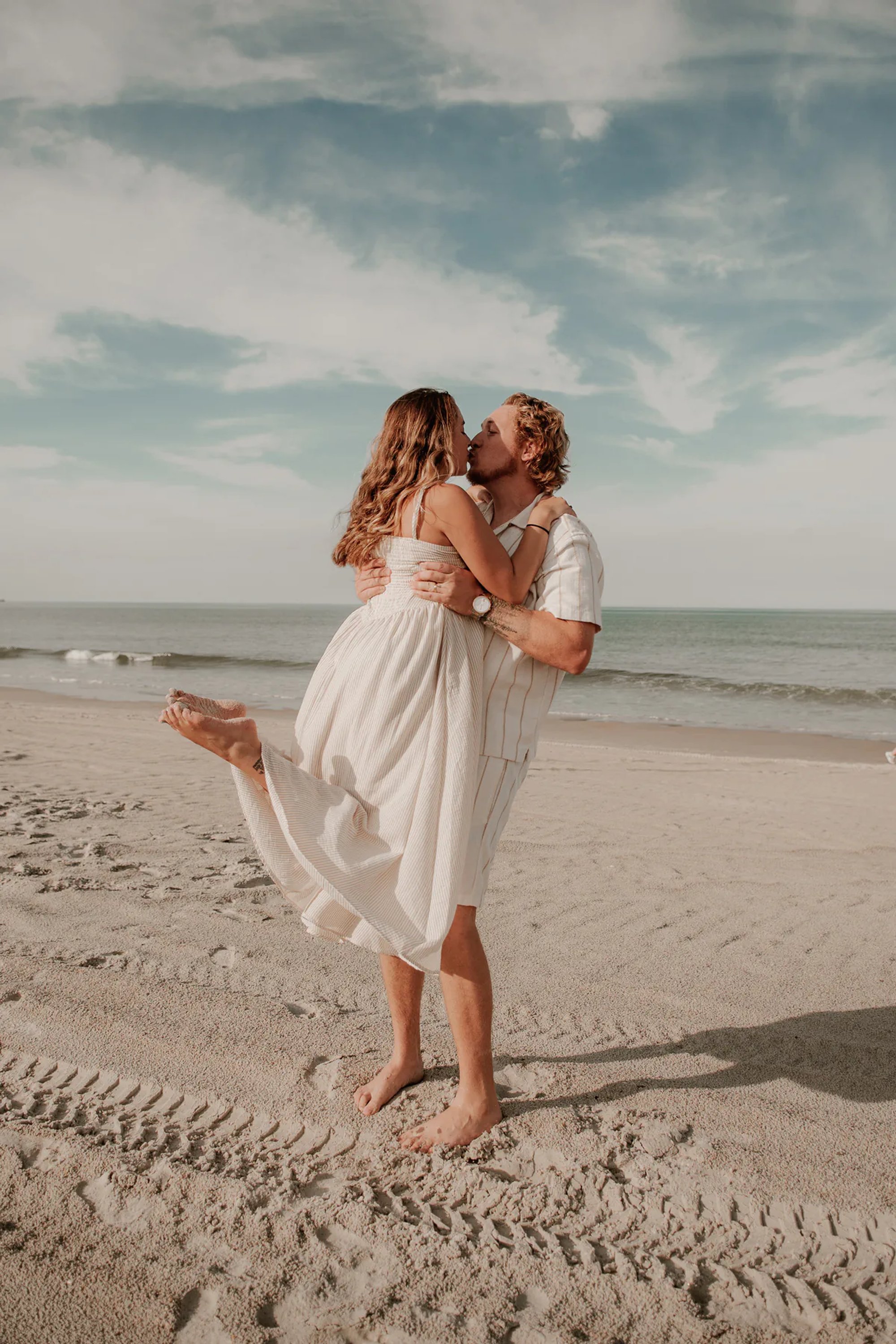 Woman lifting a young child during a playful beach portrait.