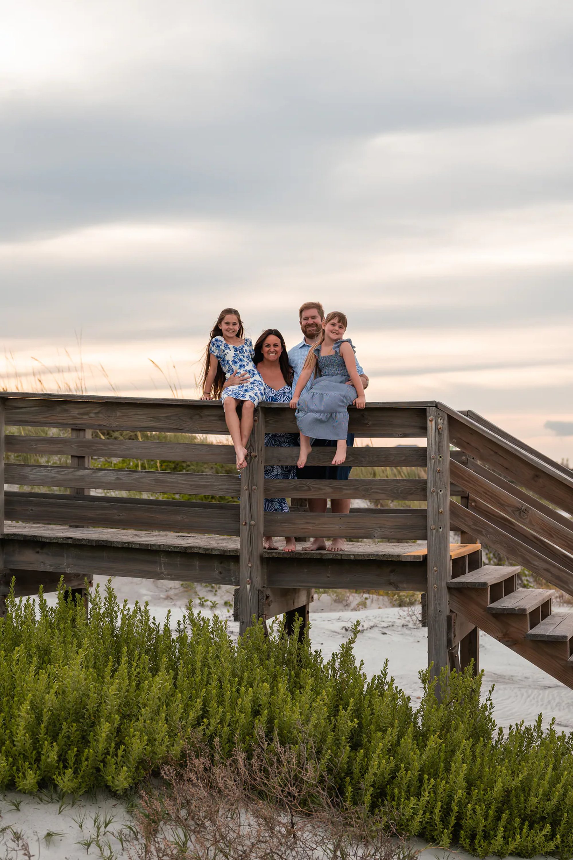 Family sitting on the wooden beach access stairs during a family photo session in Ponce Inlet.