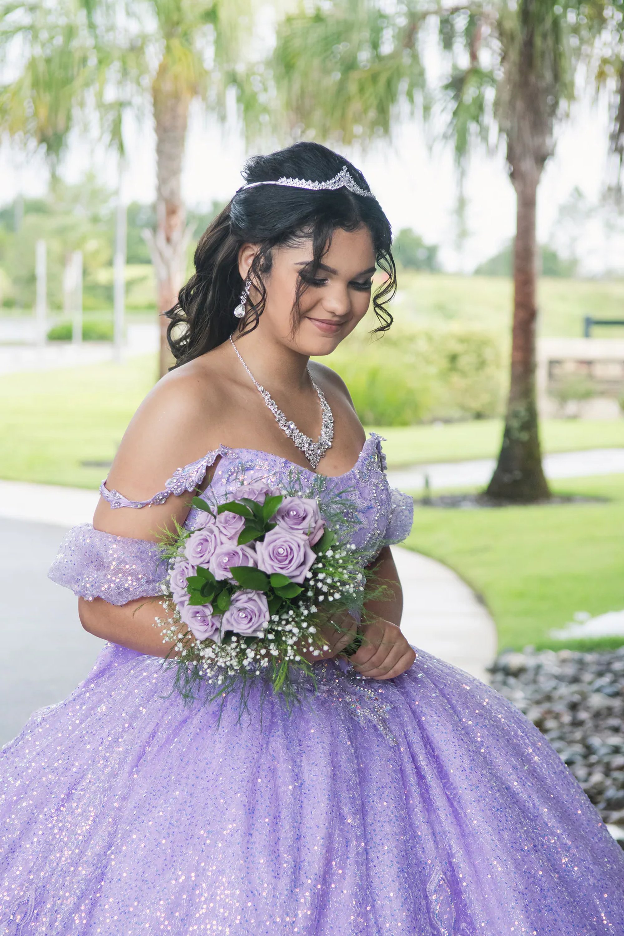 Quinceañera in a purple gown holding a matching floral bouquet.