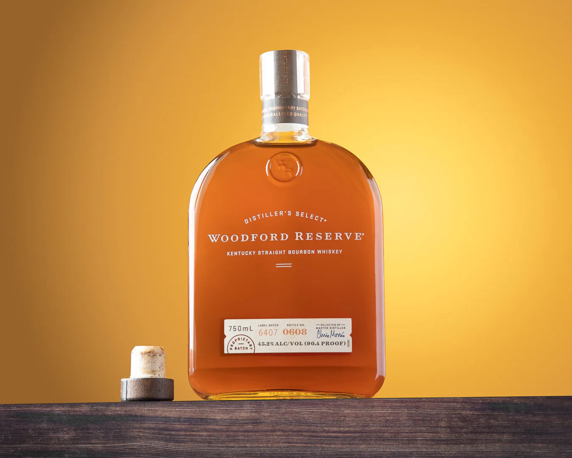 Woodford Reserve bourbon bottle with its cork on a golden background.