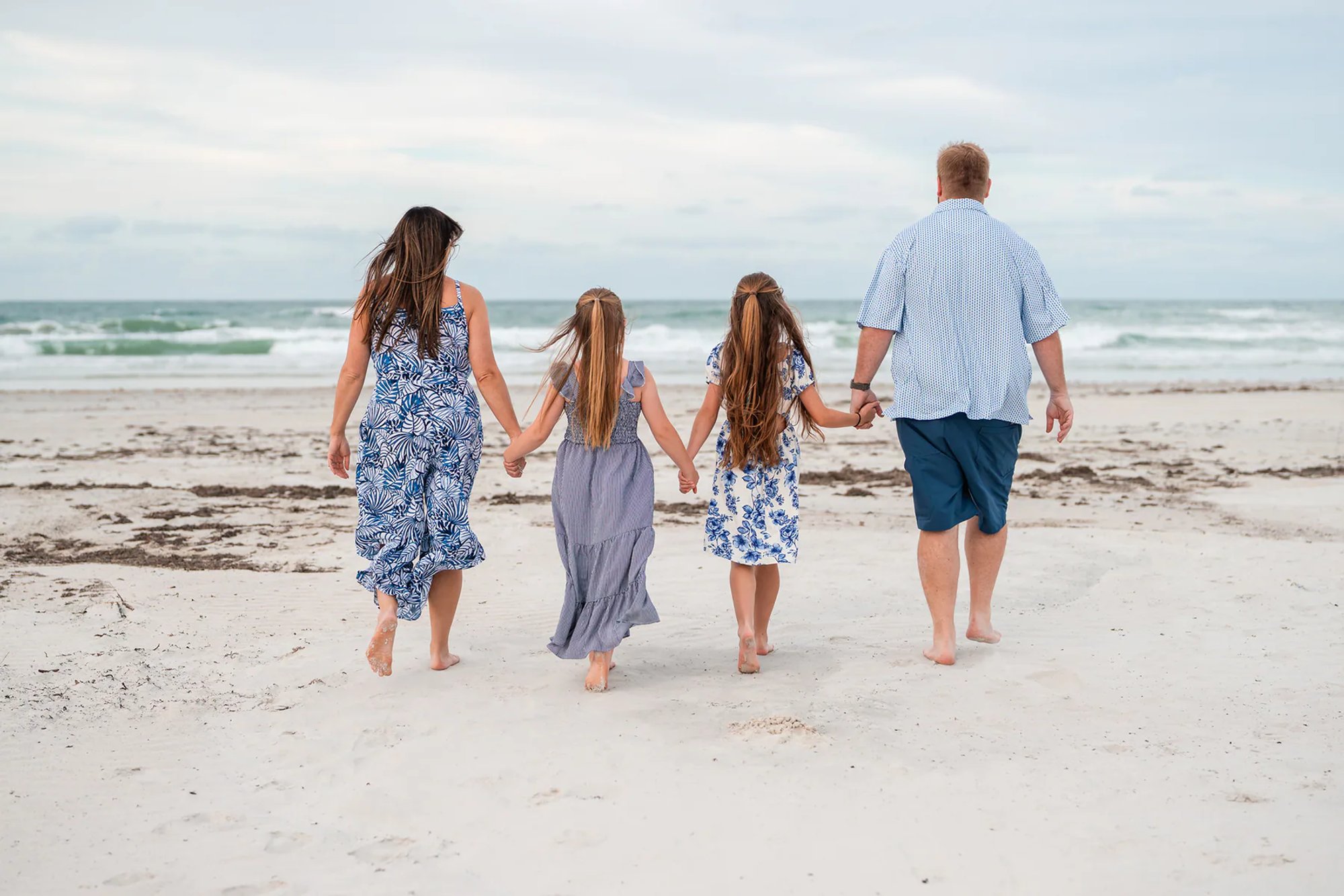 Family walking toward the ocean during a beach photography session in Ponce Inlet.