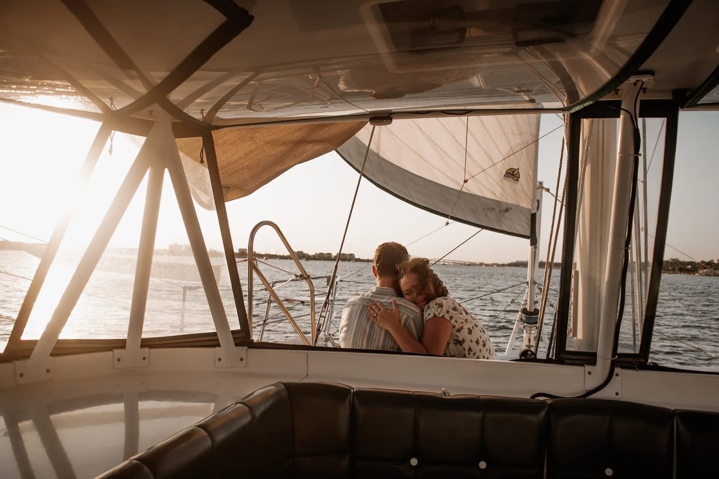 Daytona Beach sailboat engagement photos with couple sitting together on a boat at sunset