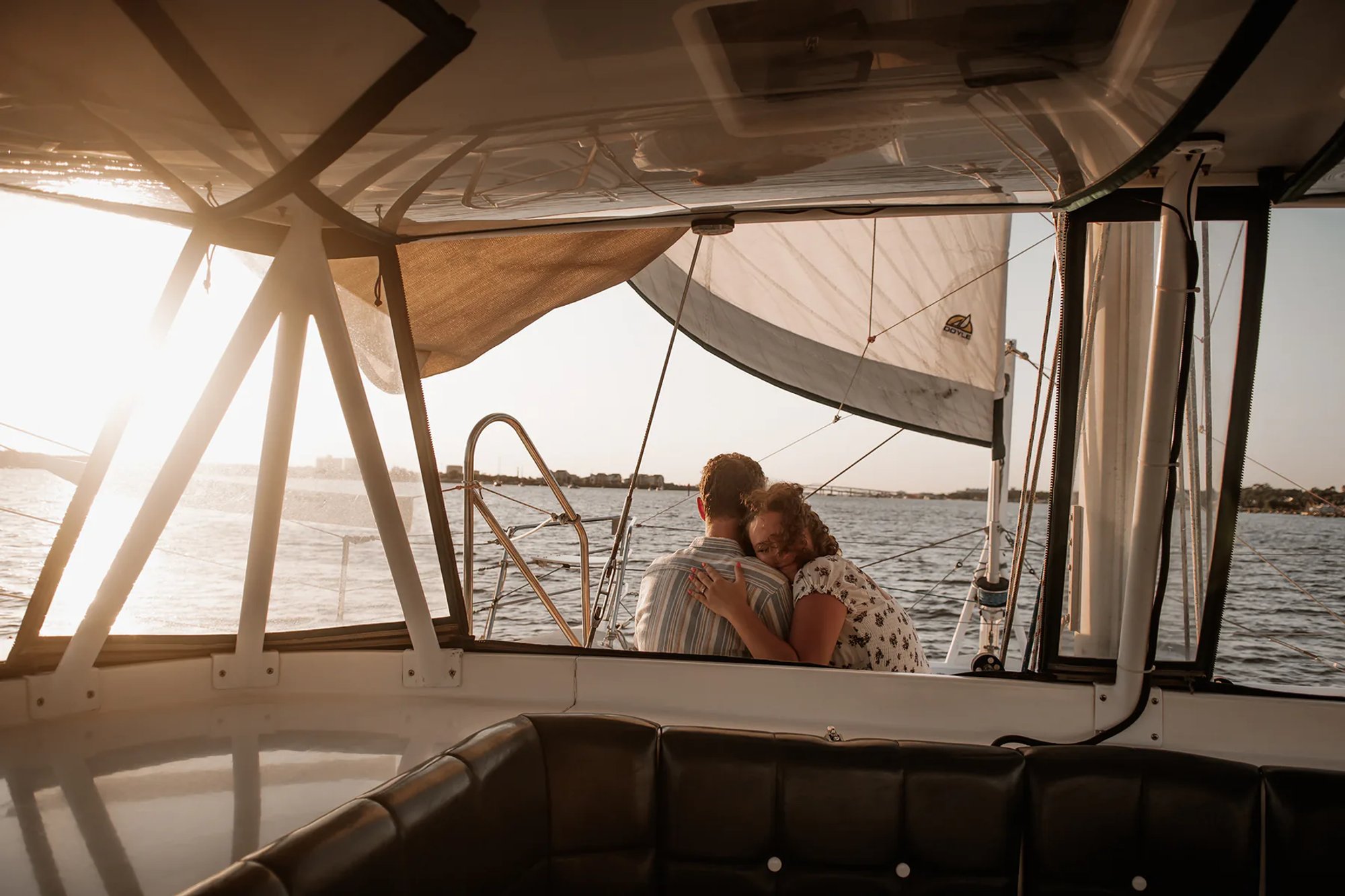 Daytona Beach sailboat engagement photos with couple sitting together on a boat at sunset