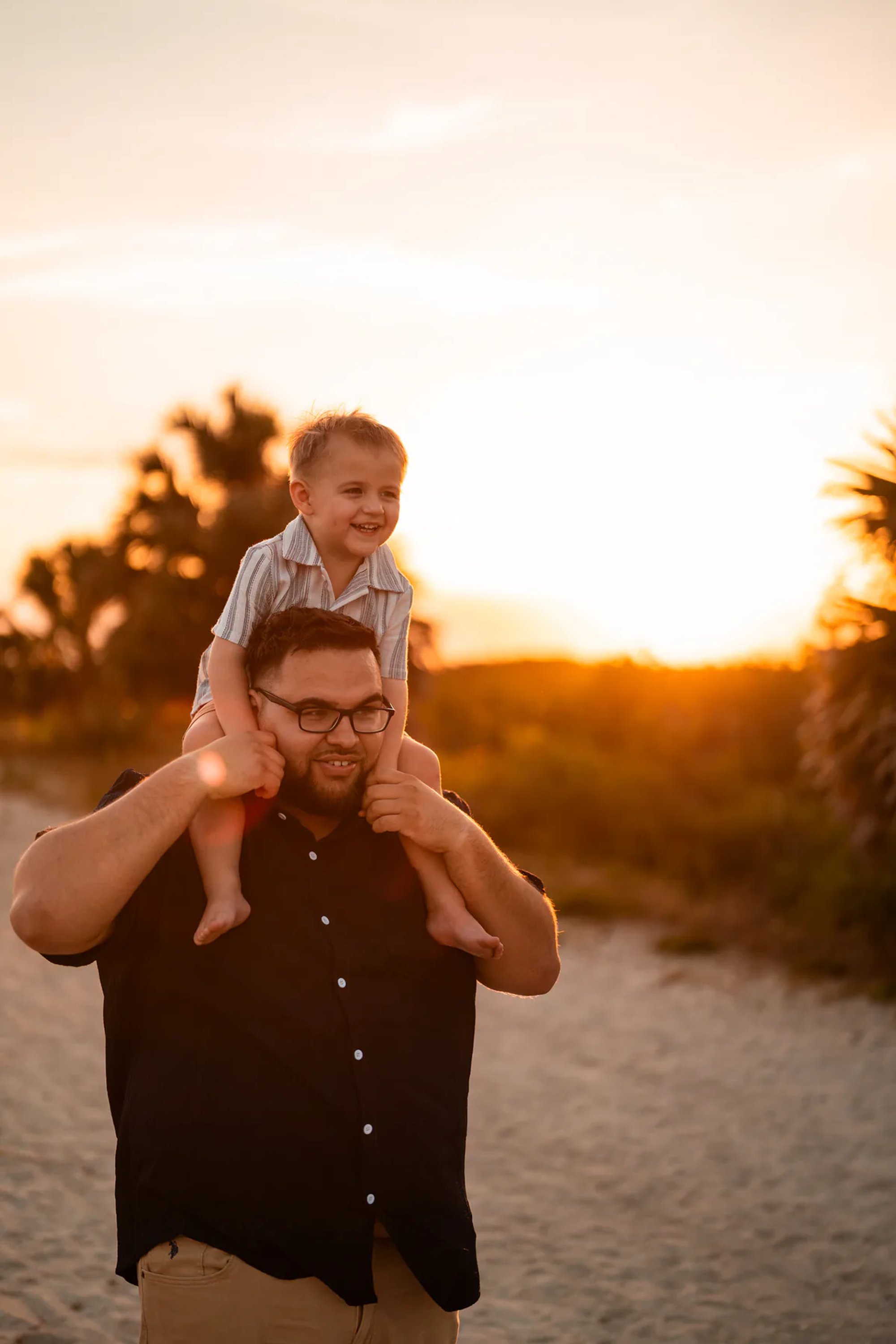 Father carrying child on shoulders during sunset family photos at Ponce Inlet Beach