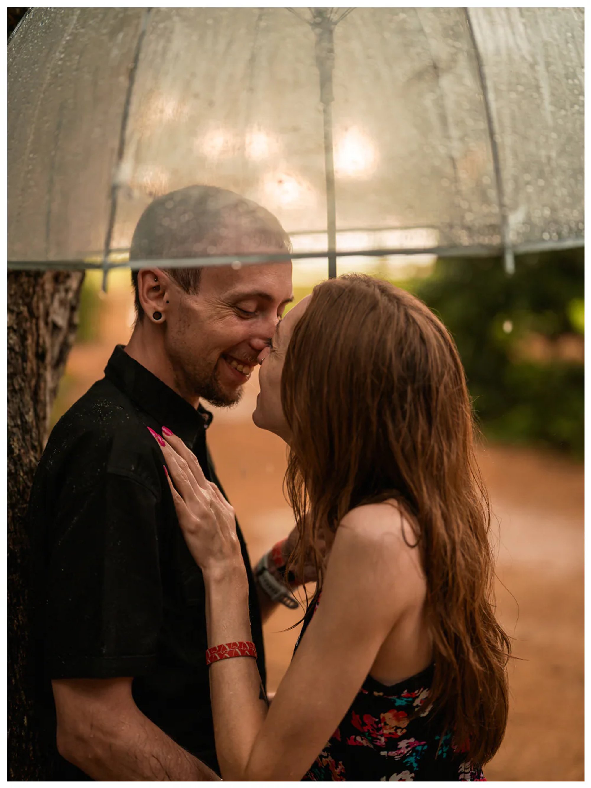 Close portrait of a couple smiling at each other beneath a rain-speckled umbrella at Washington Oaks.