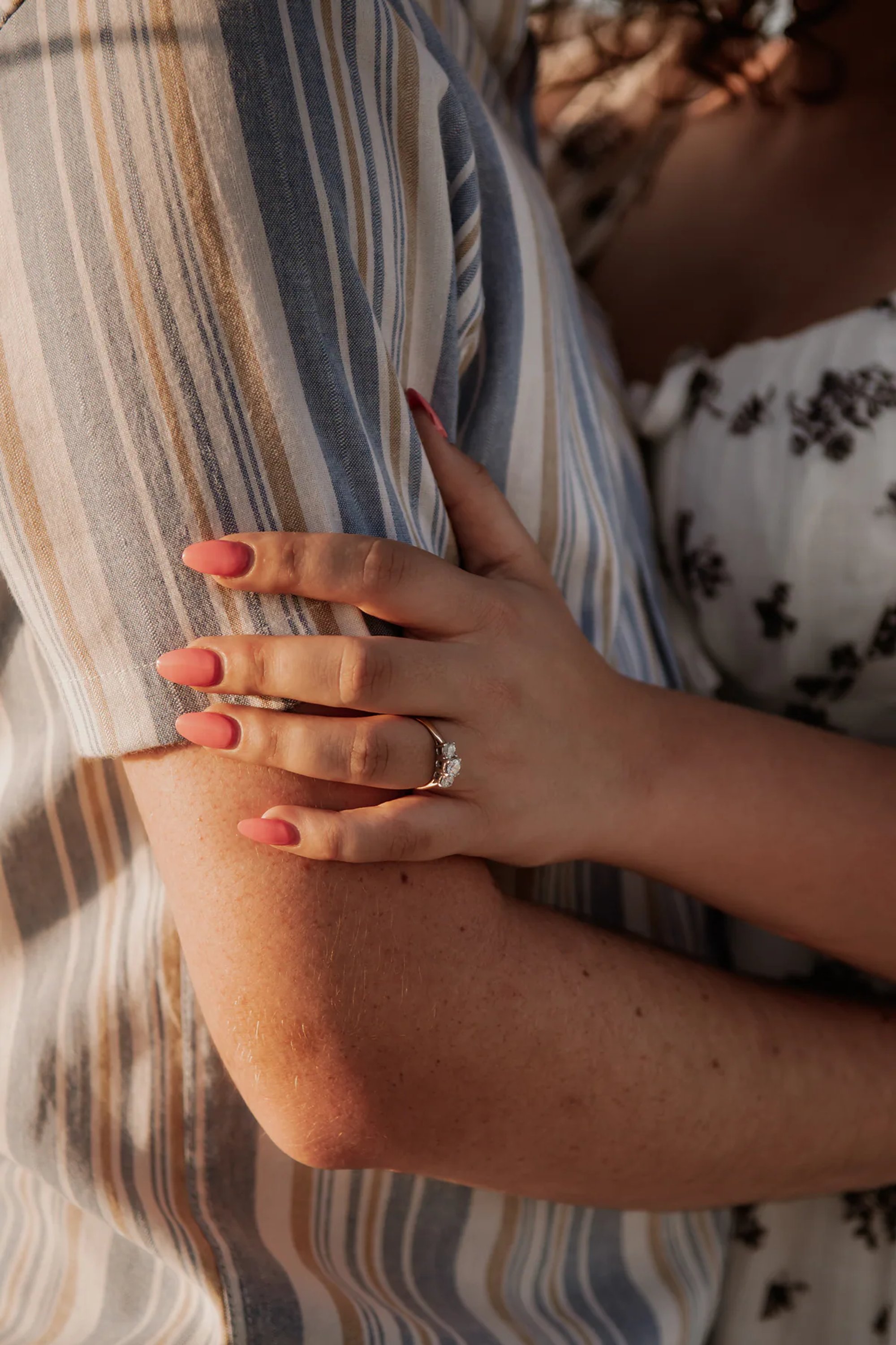 Engagement ring detail photo with couple embracing during Daytona Beach sailboat session
