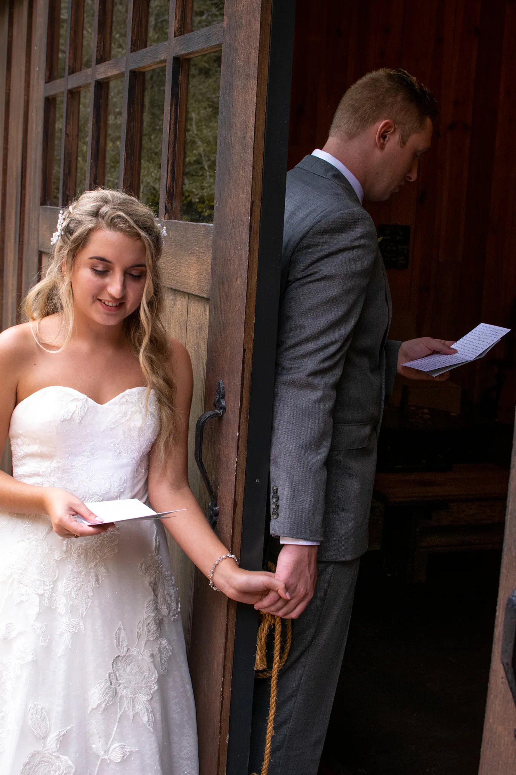 Bride and groom holding hands around a doorway before the ceremony.