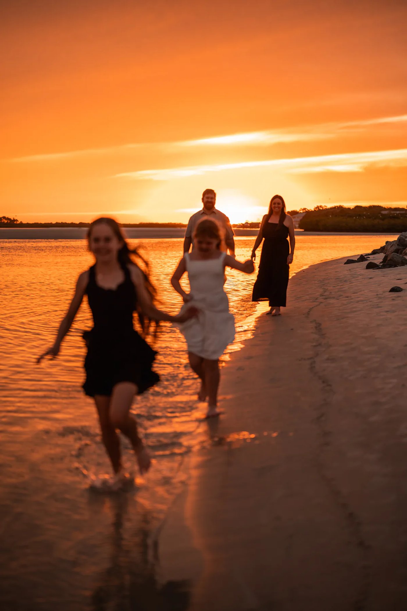 Family walking along the shoreline during a sunset beach photography session in Ponce Inlet, Florida.