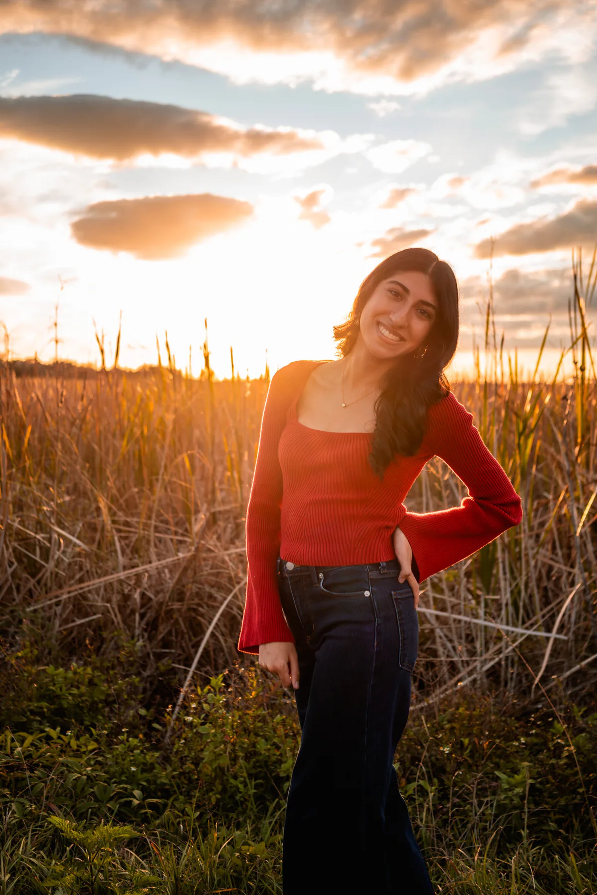 Ahaana posing in tall grass for senior photos near DeLeon Springs