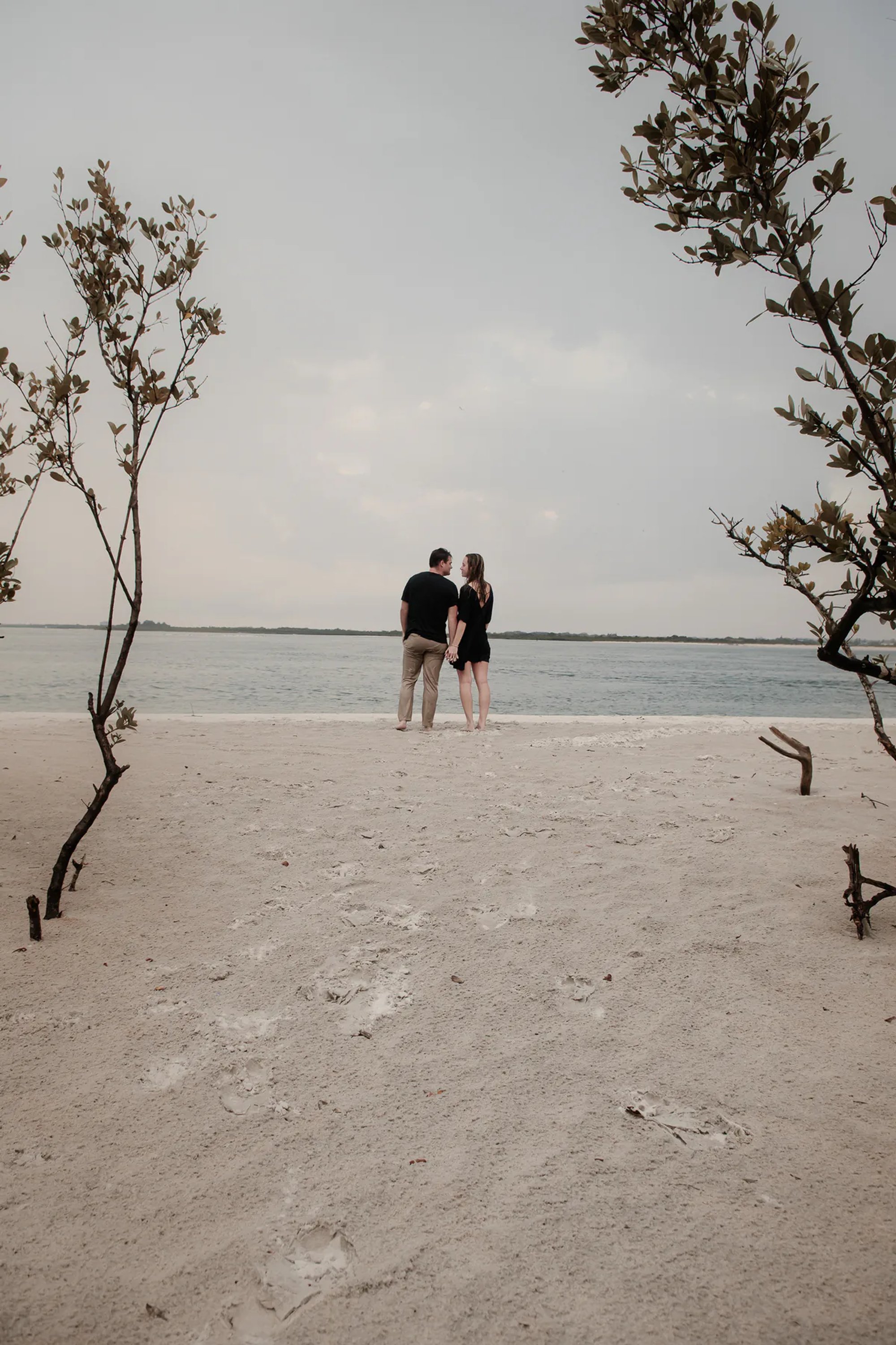 Ponce Inlet engagement photos with couple walking on the beach near the water and coastal trees