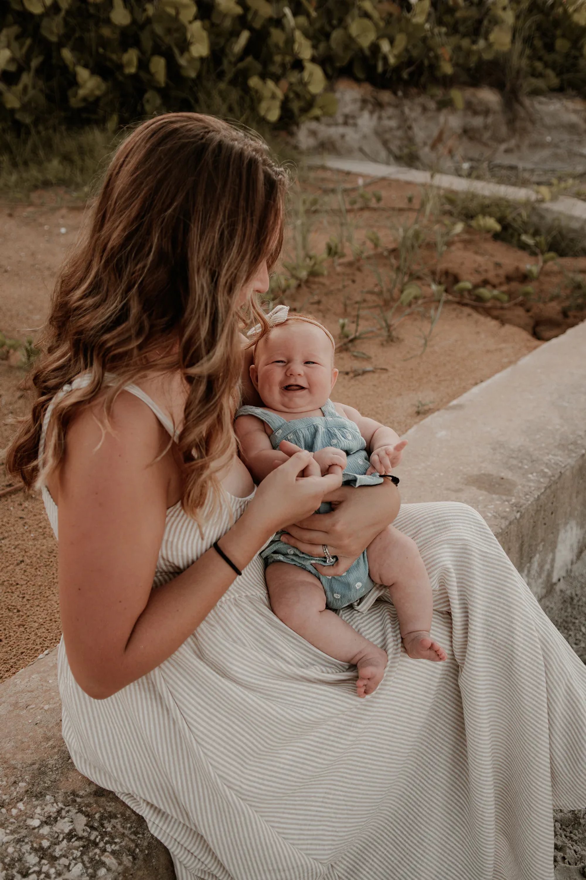 Mother holding her baby beside the water.