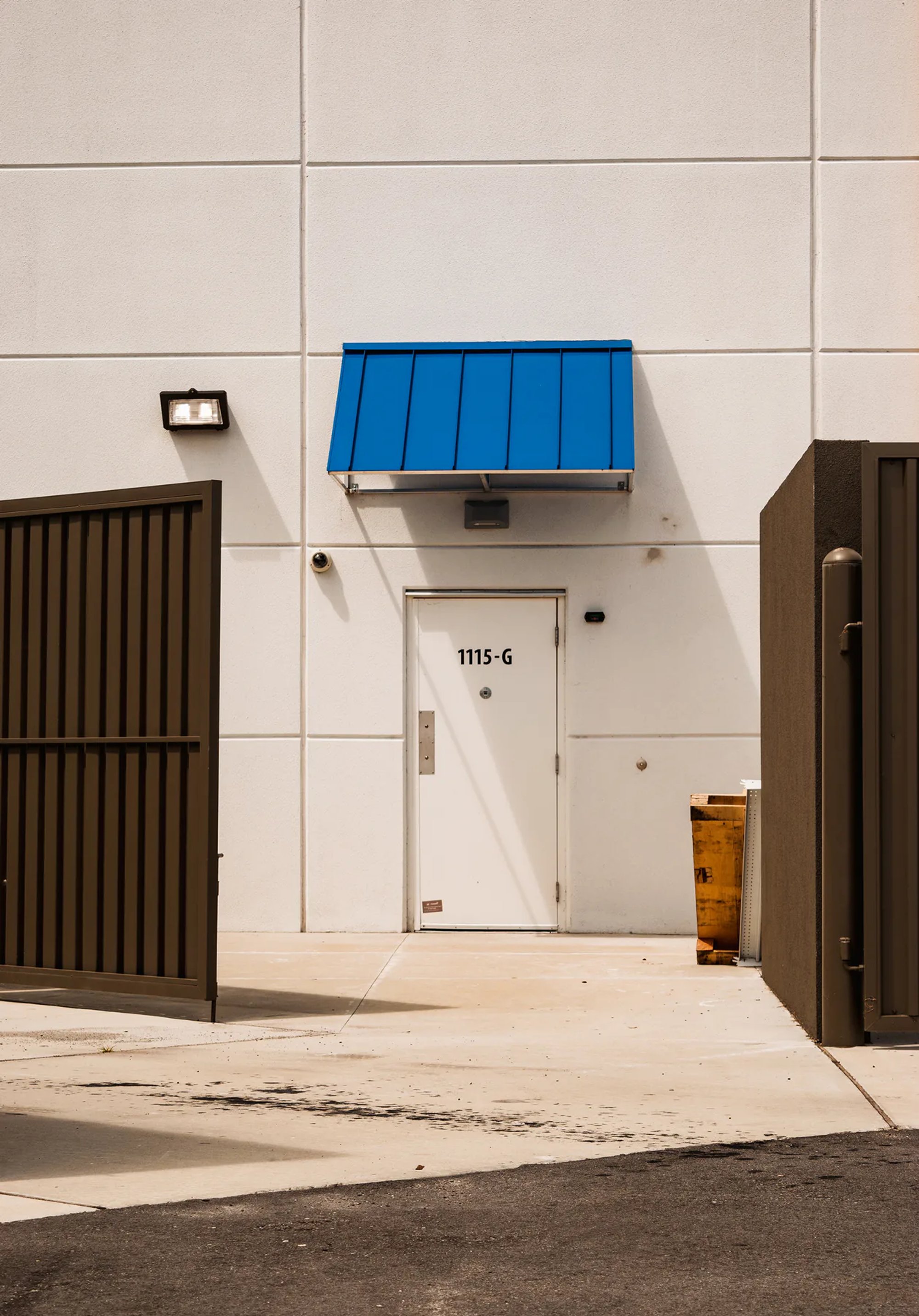 White industrial building entrance with a bright blue awning.