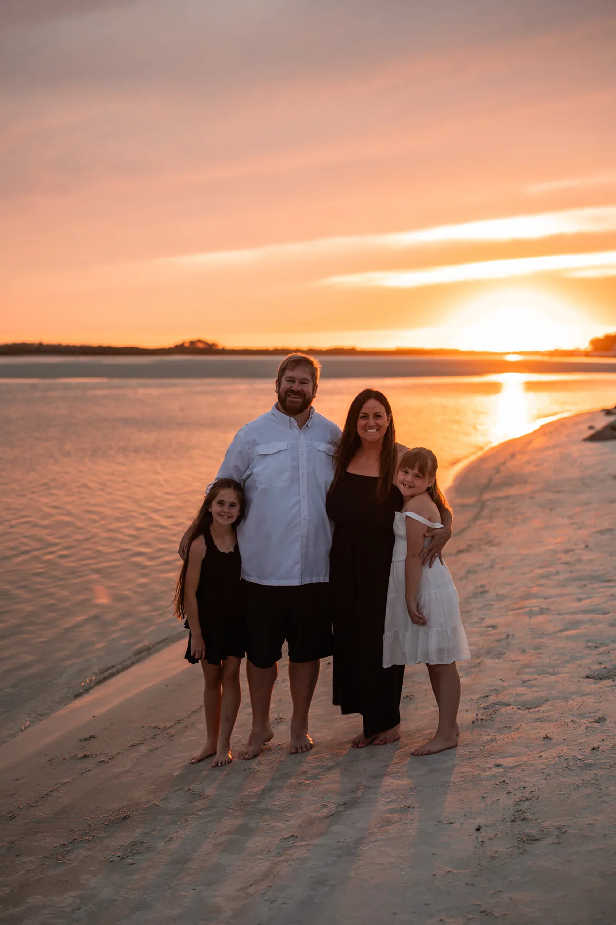 Family portrait on the sand with the sunset behind them at Ponce Inlet Beach.